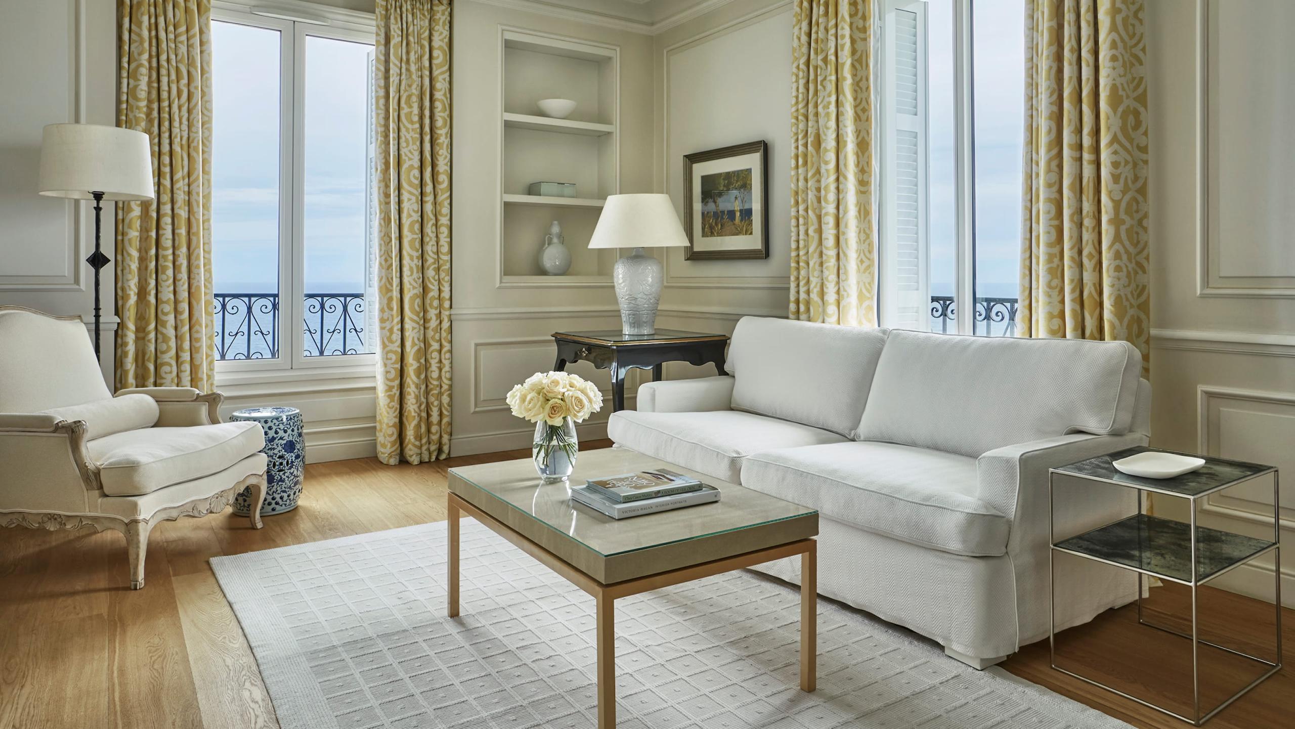 Cream parlor with gold curtains, upholstered seating, and sea-view doors