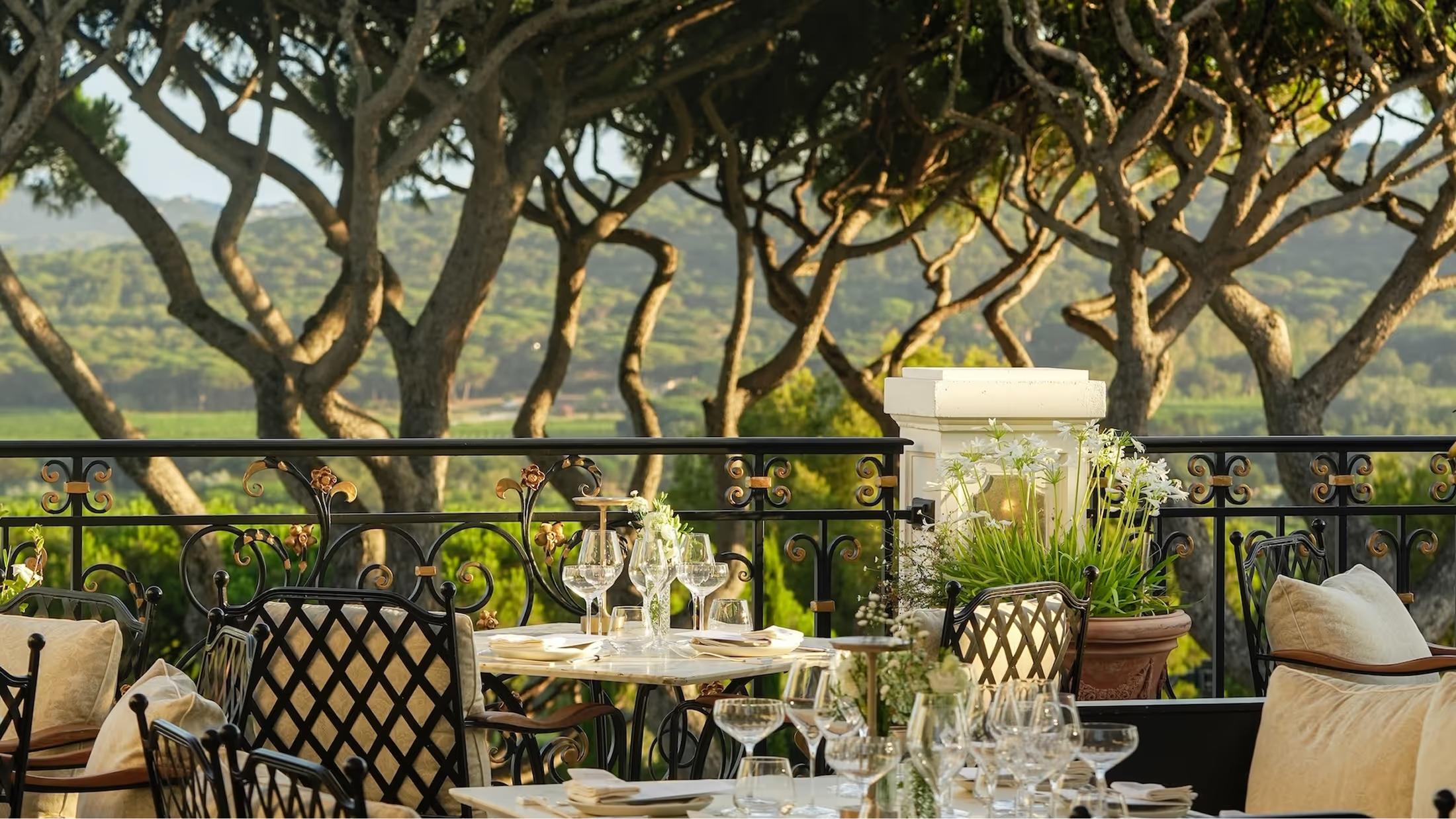 Dining area shaded by stone columns and vine canopy overlooking the valley