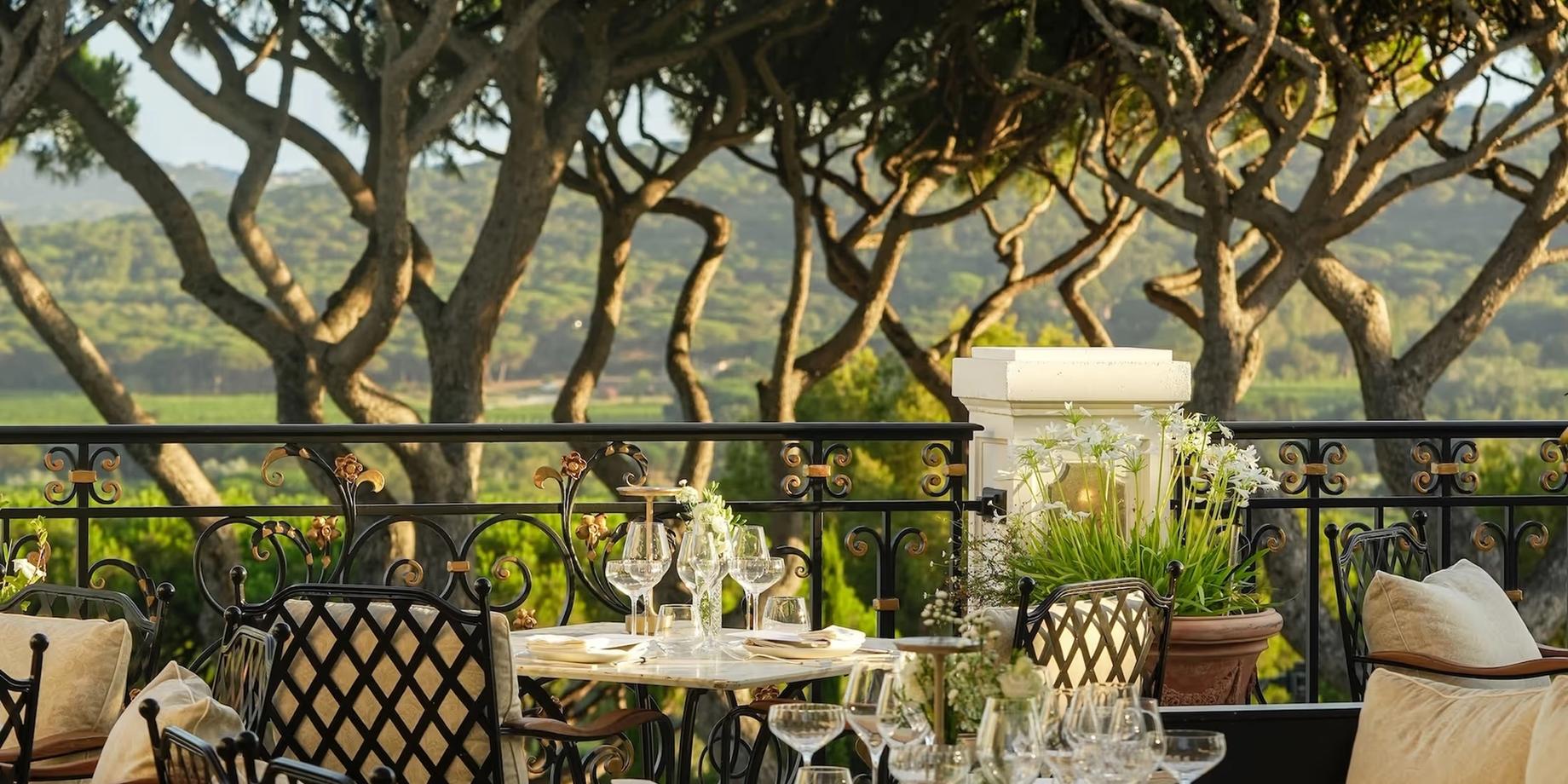 Dining area shaded by stone columns and vine canopy overlooking the valley
