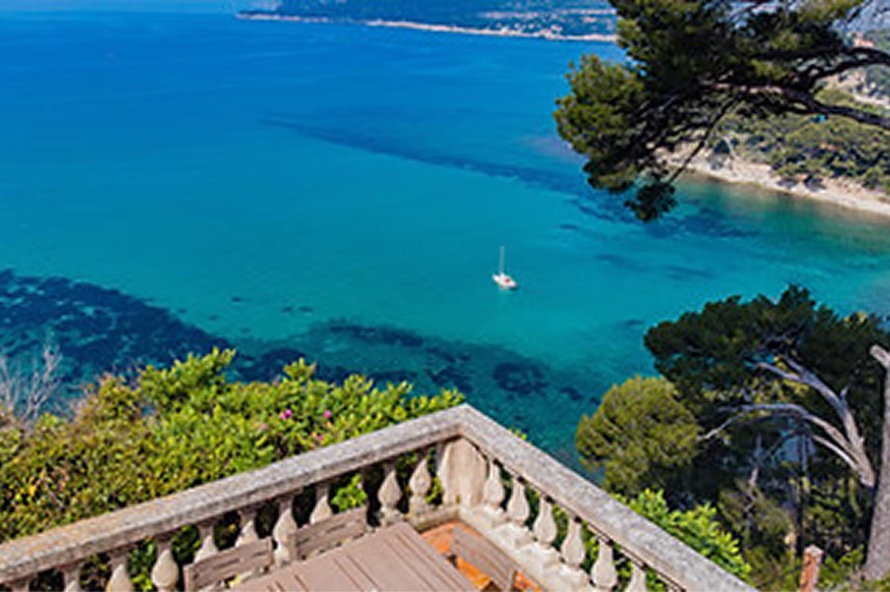 Le Domaine de Canaille: terracotta terrace with stone balustrade overlooking turquoise Mediterranean, sailboat on cove, pine forest below