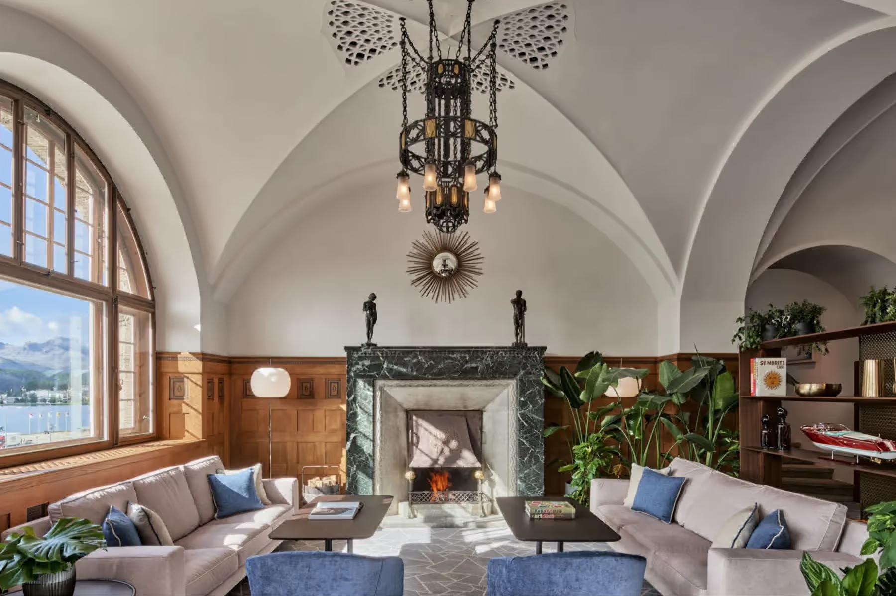 Grace La Margna St. Moritz: historic lobby with arched ceiling, ornate chandelier, fireplace, and blue seating accents