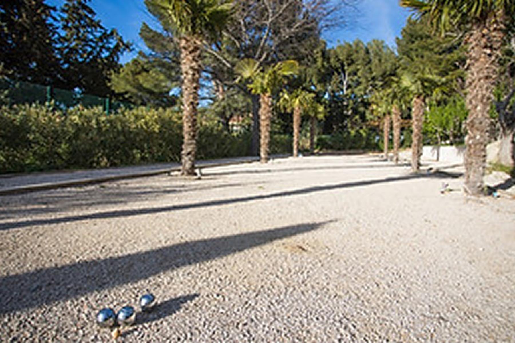Le Domaine de Canaille: paved courtyard with tall stone column shading, palm trees, and surrounding stonework