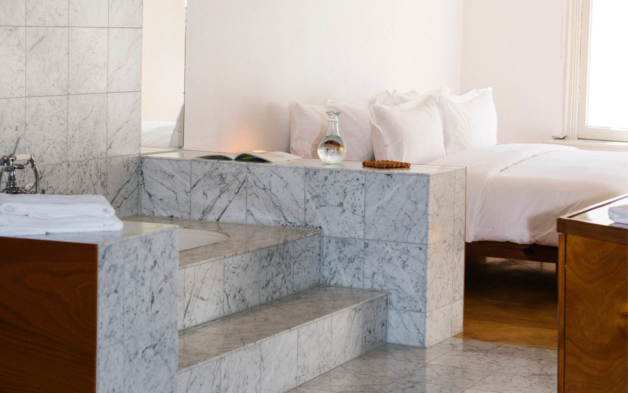 A guest room at Carmen, a marble bath with steps beside a white bed