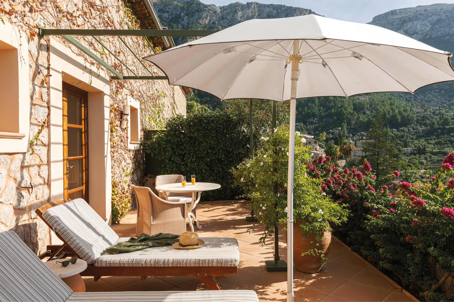 La Residencia: private terrace with lounge chairs, cream umbrella, and Mediterranean hillside view