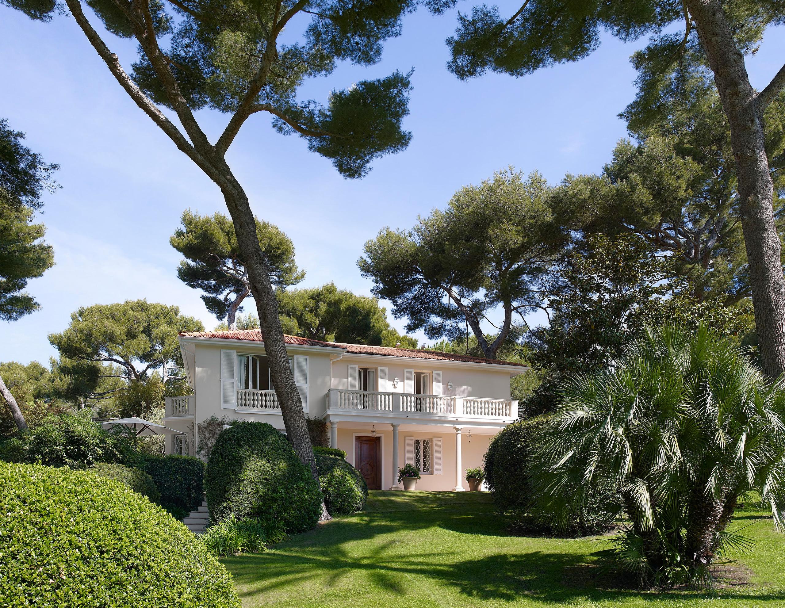 Hôtel du Cap-Eden-Roc: a villa exterior set under stone pines with a linear swimming pool and terracotta paving