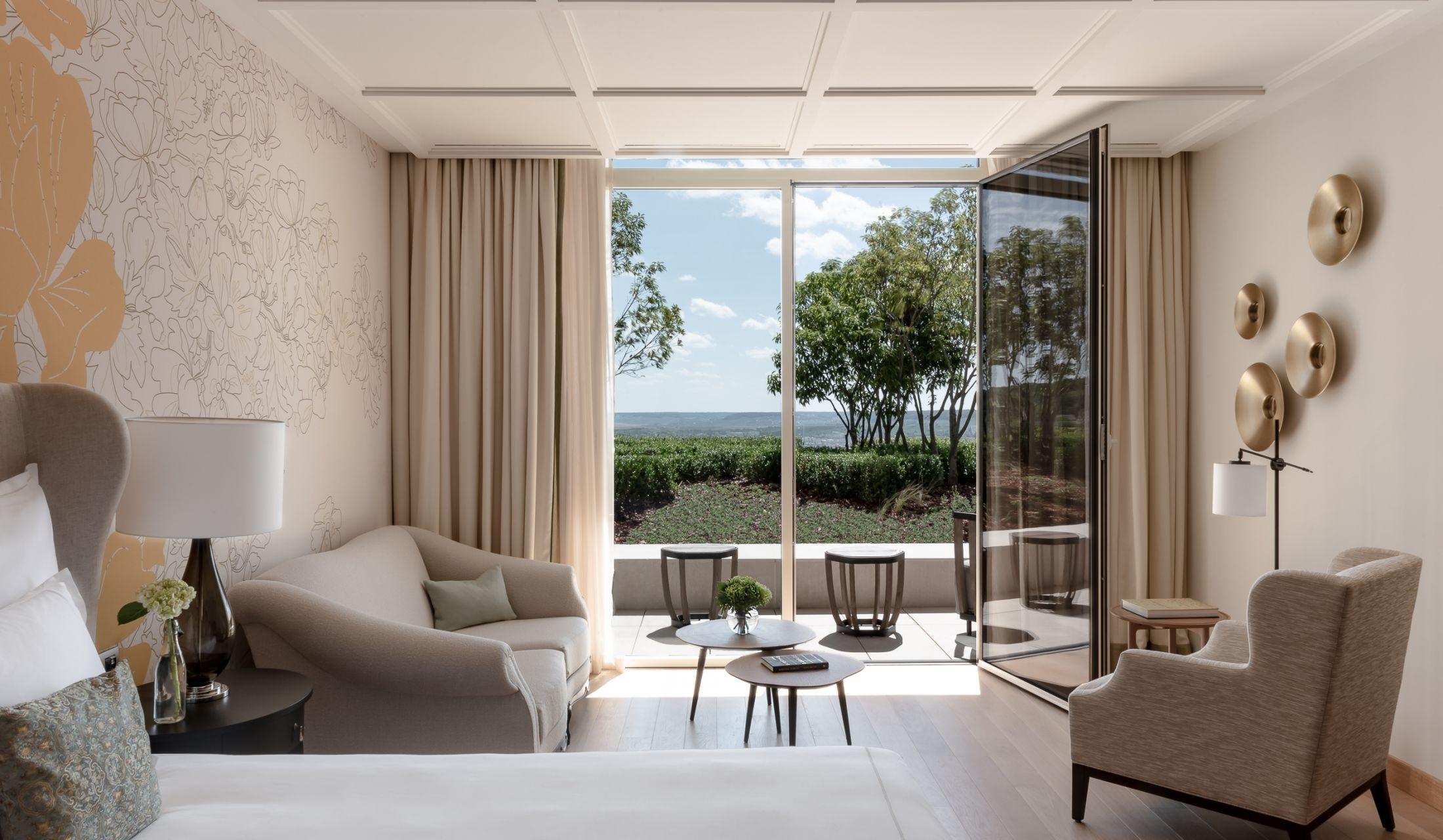 Suite interior with neutral palette, layered seating, and glass doors to a private terrace