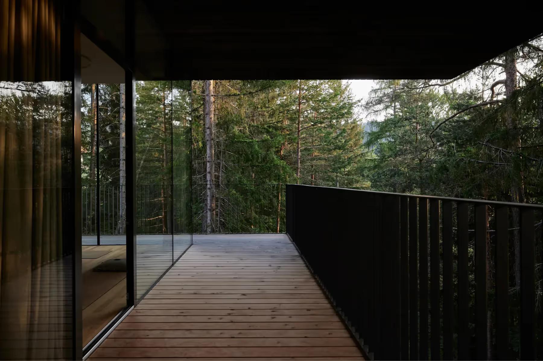 Hotel Saltus: wooden deck with glass railing overlooking forested mountainous terrain