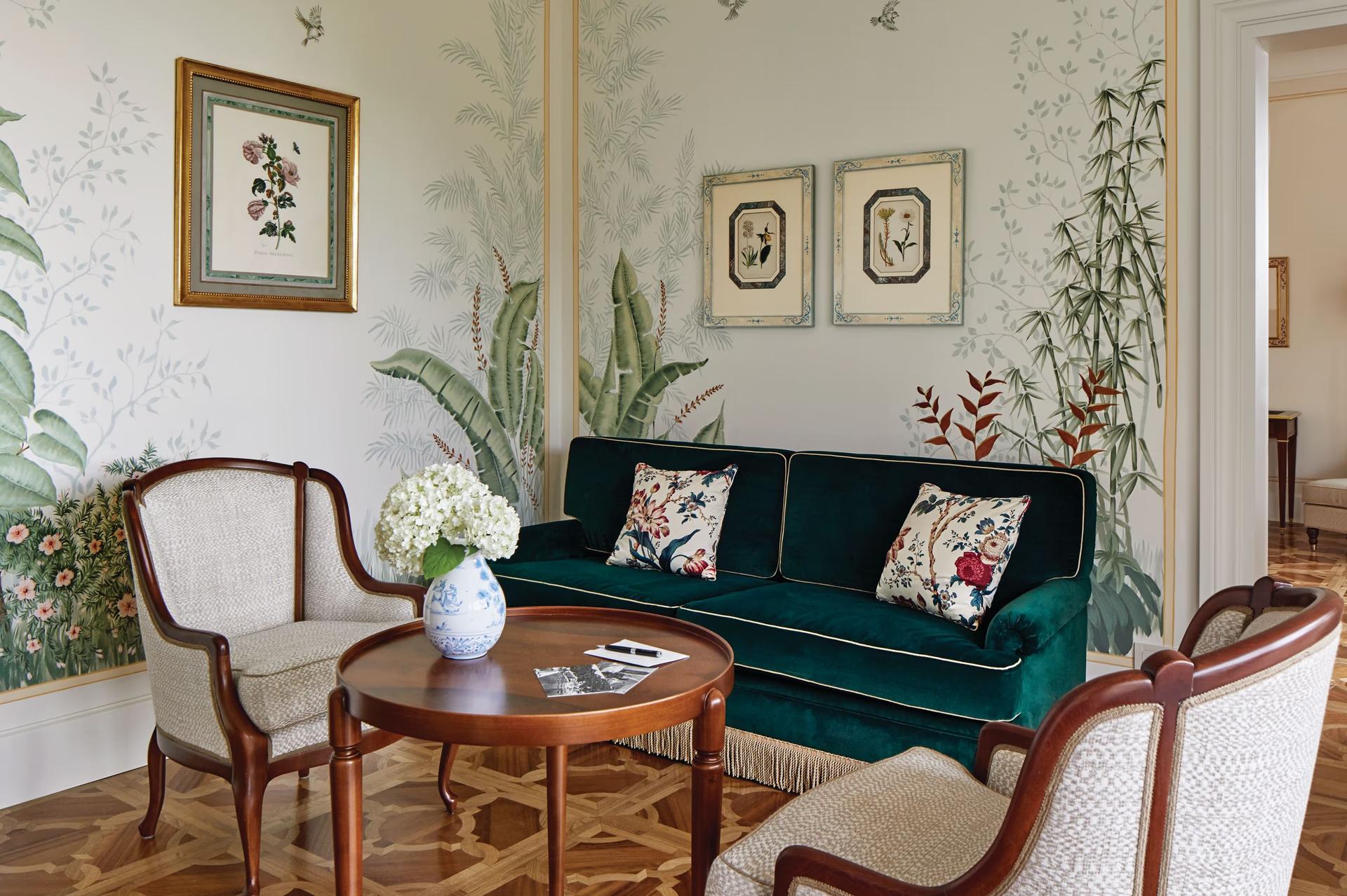 A living room with green sofa, botanical décor, and glass doors opening to terrace