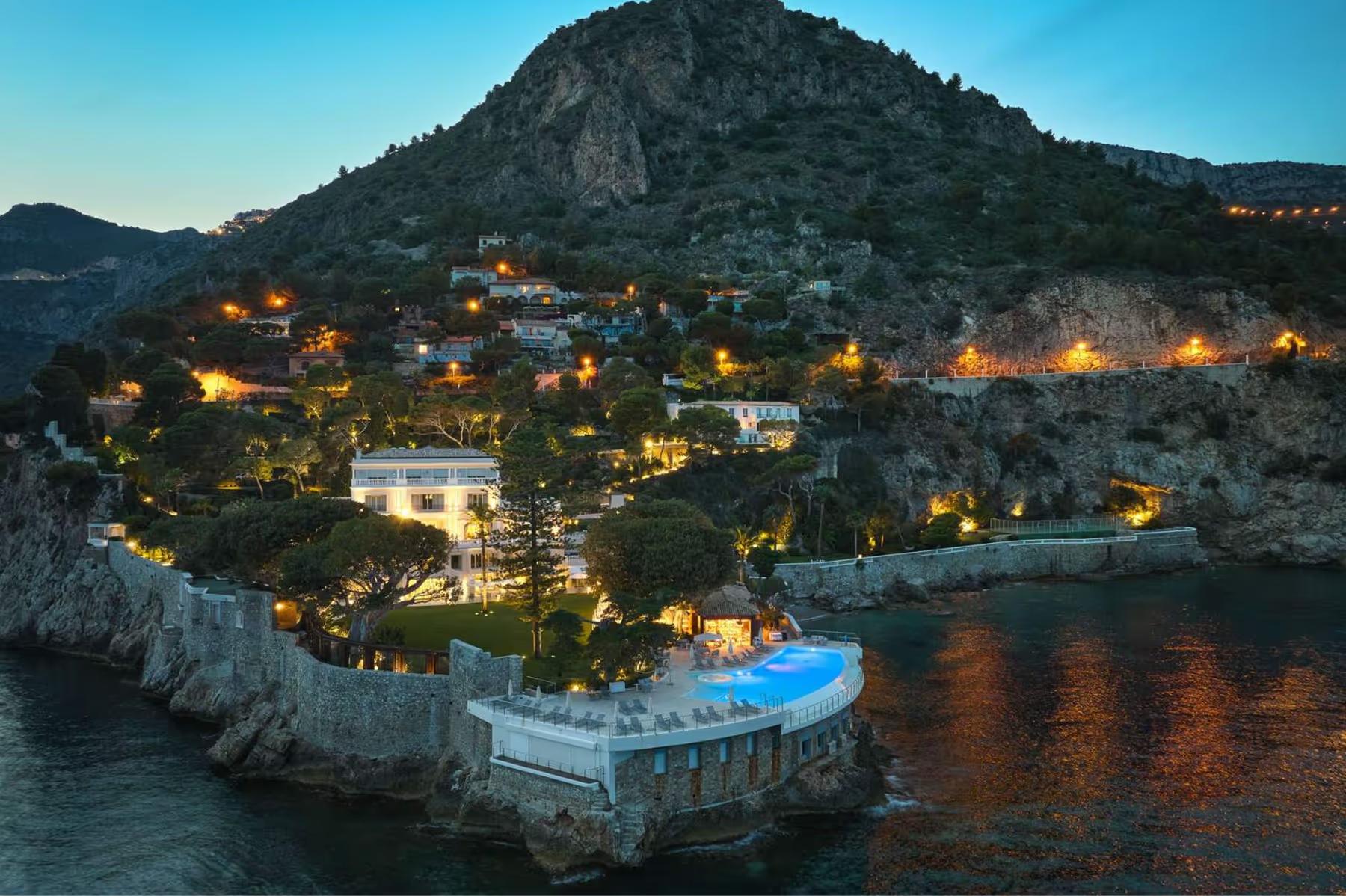 Hotel Cap-Estel: evening view of the hotel compound on a cliffside with lit structures