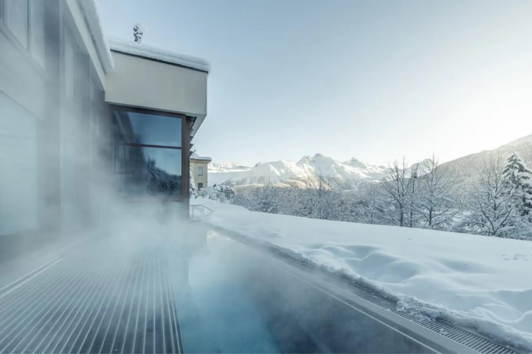 Kulm Hotel St. Moritz: a skier in orange jacket carving turns down a perfectly groomed Alpine slope