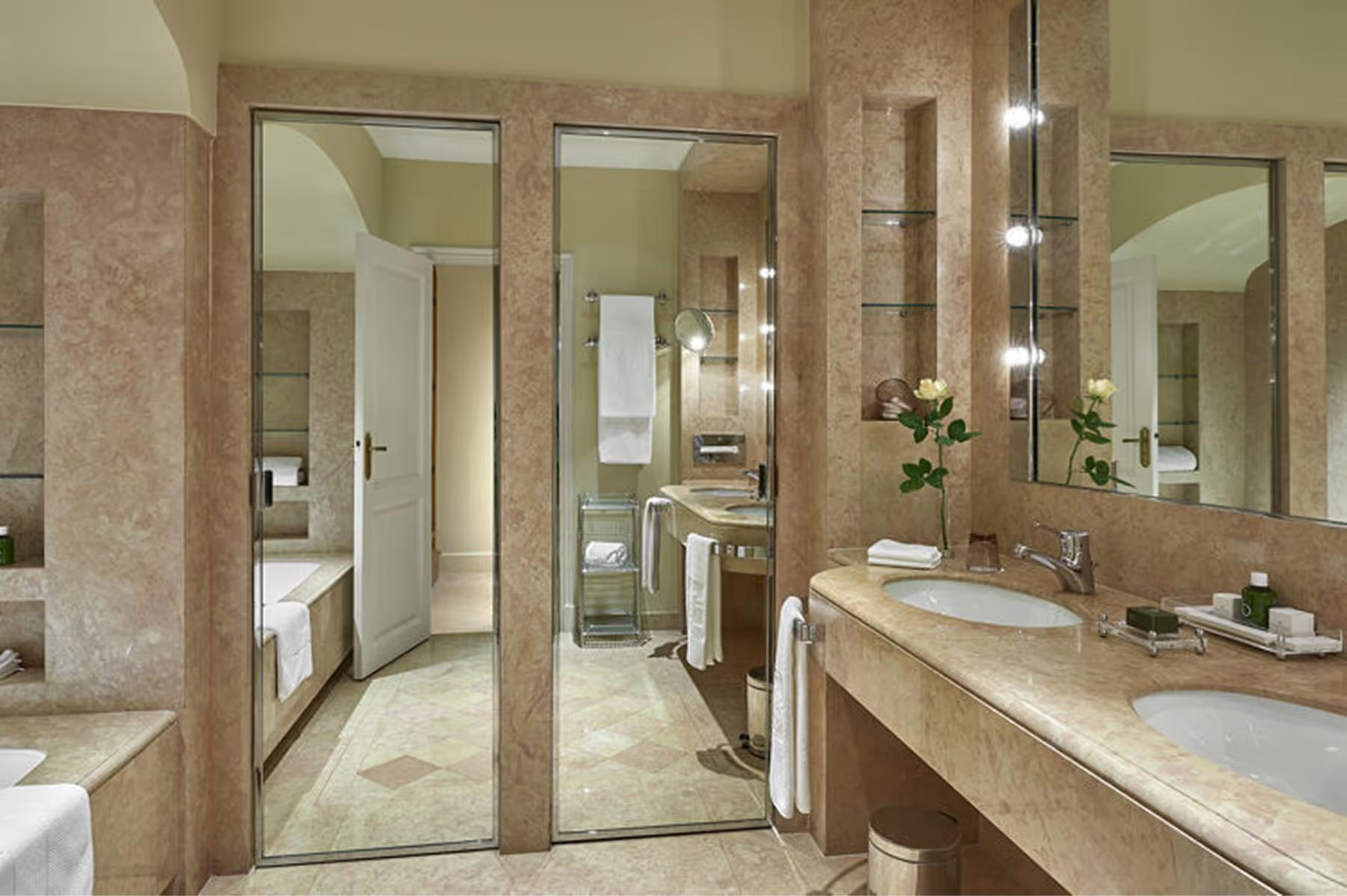 Spa bathroom with marble and dual vanities with mirror lighting