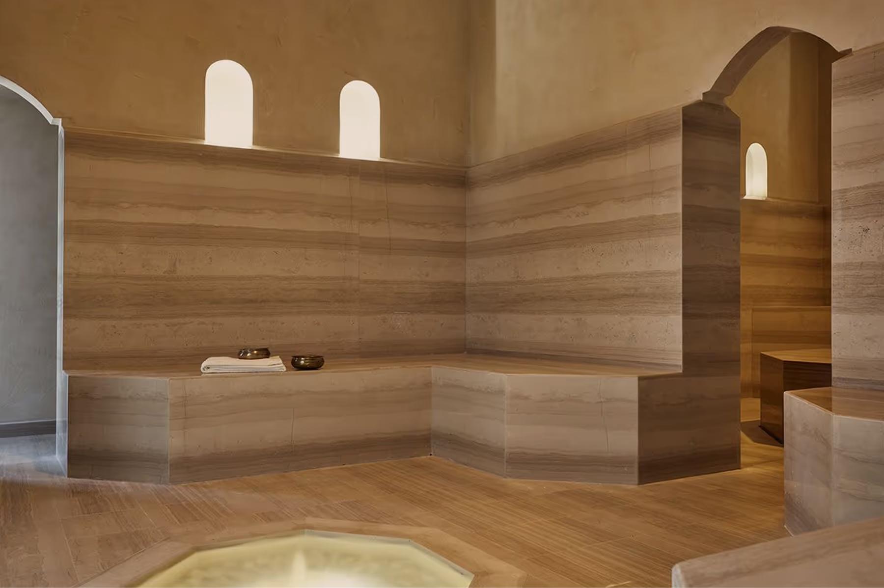 Cap Rocat: a modern spa room with pale wood paneling, arched alcoves, and soft recessed lighting