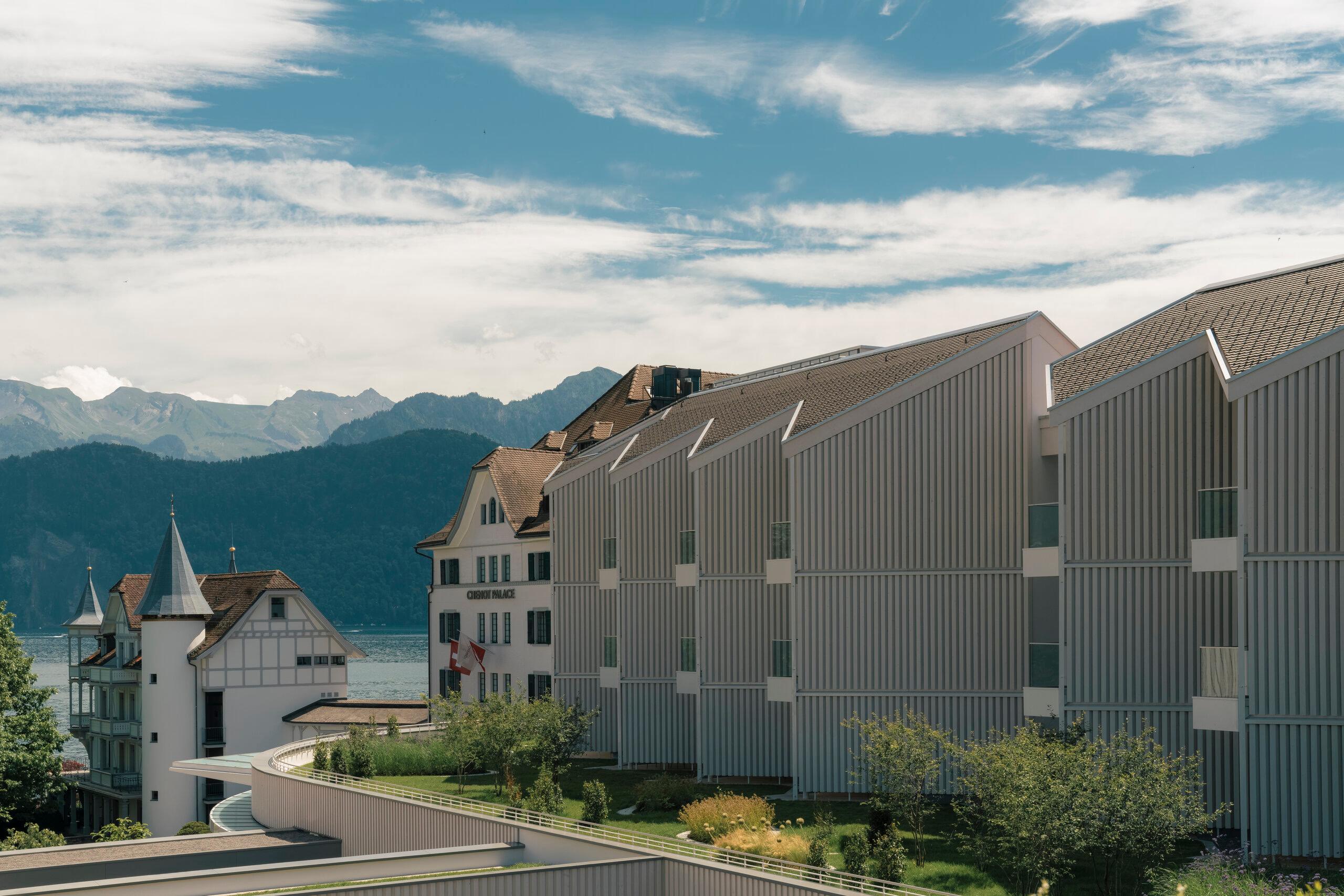 Building exterior in corrugated metal with lake and mountain backdrop against blue sky