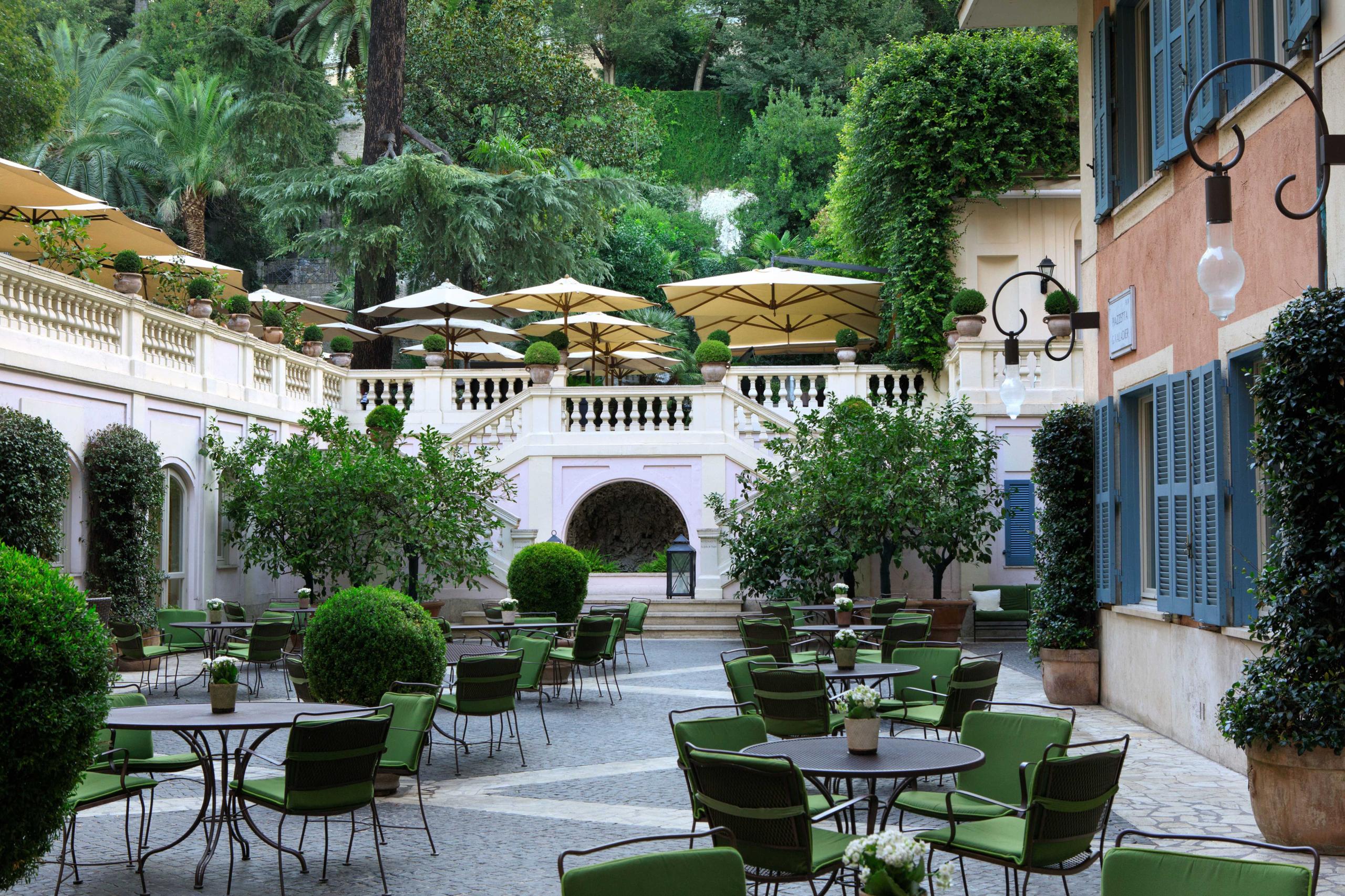 Hotel de Russie: tiered garden courtyard with columns, greenery, and scattered seating areas