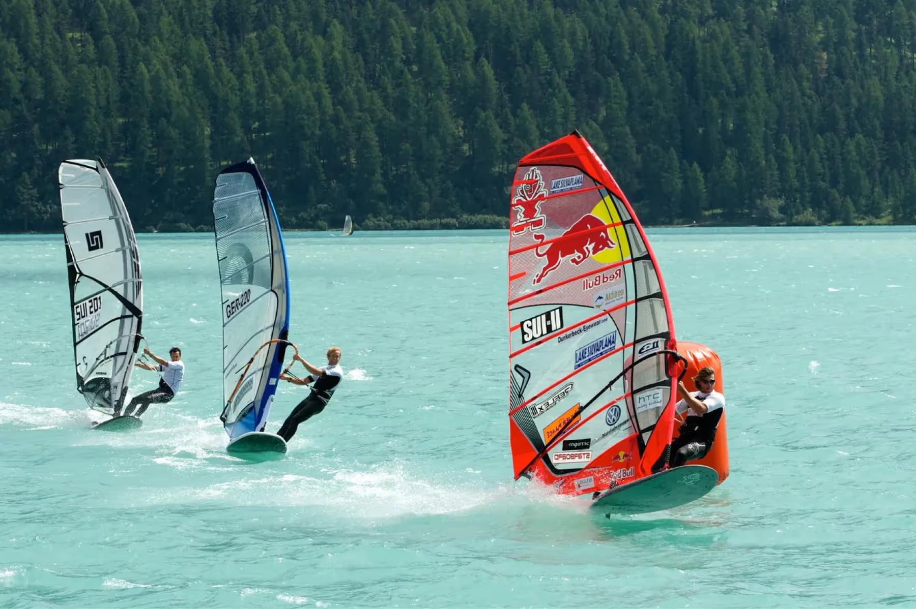 Kulm Hotel St. Moritz: windsurfing and sailing boards on a turquoise mountain lake framed by peaks