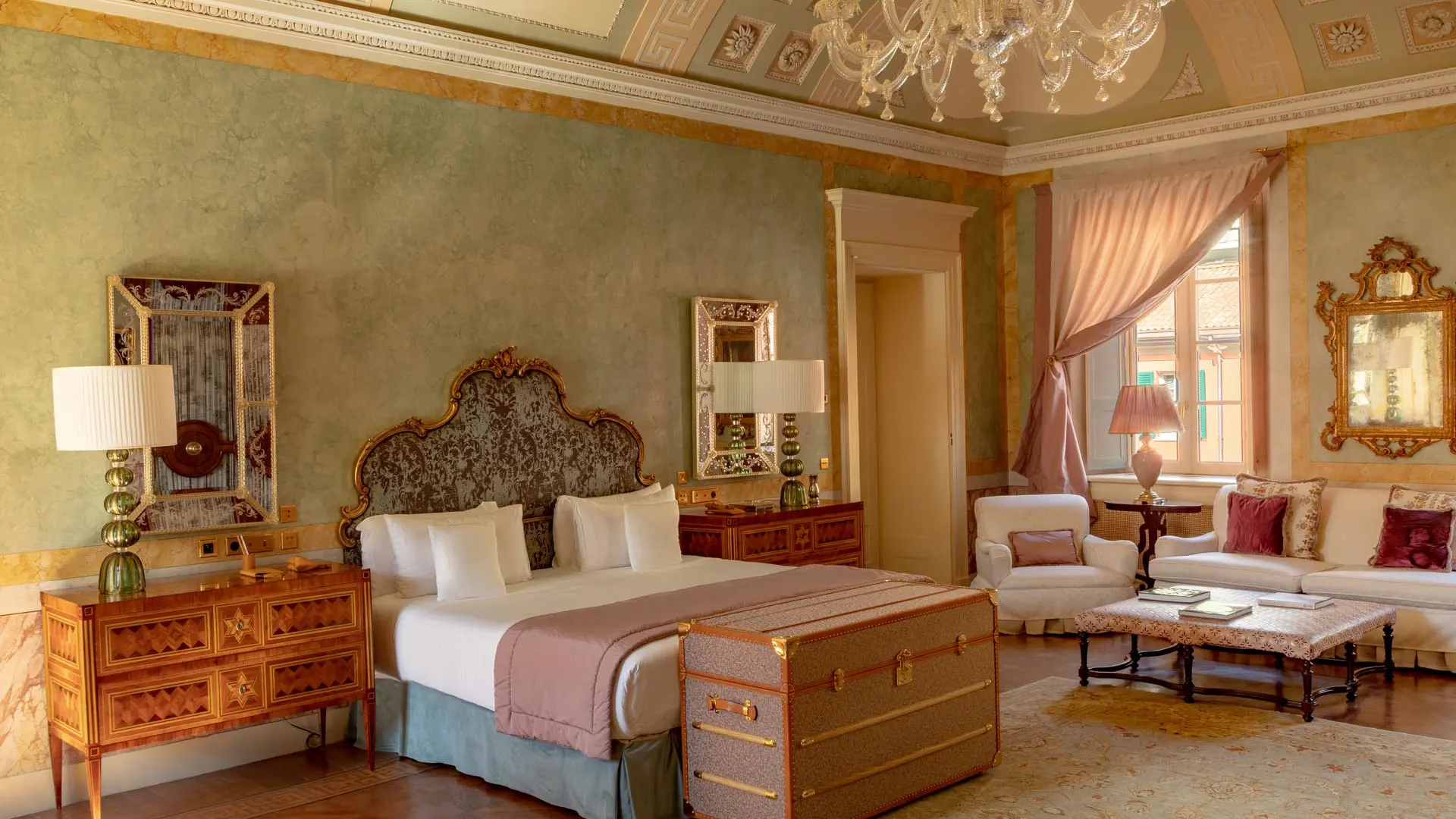 Passalacqua: a bedroom with rose ceiling, wood furniture, and gold fabric canopy curtains