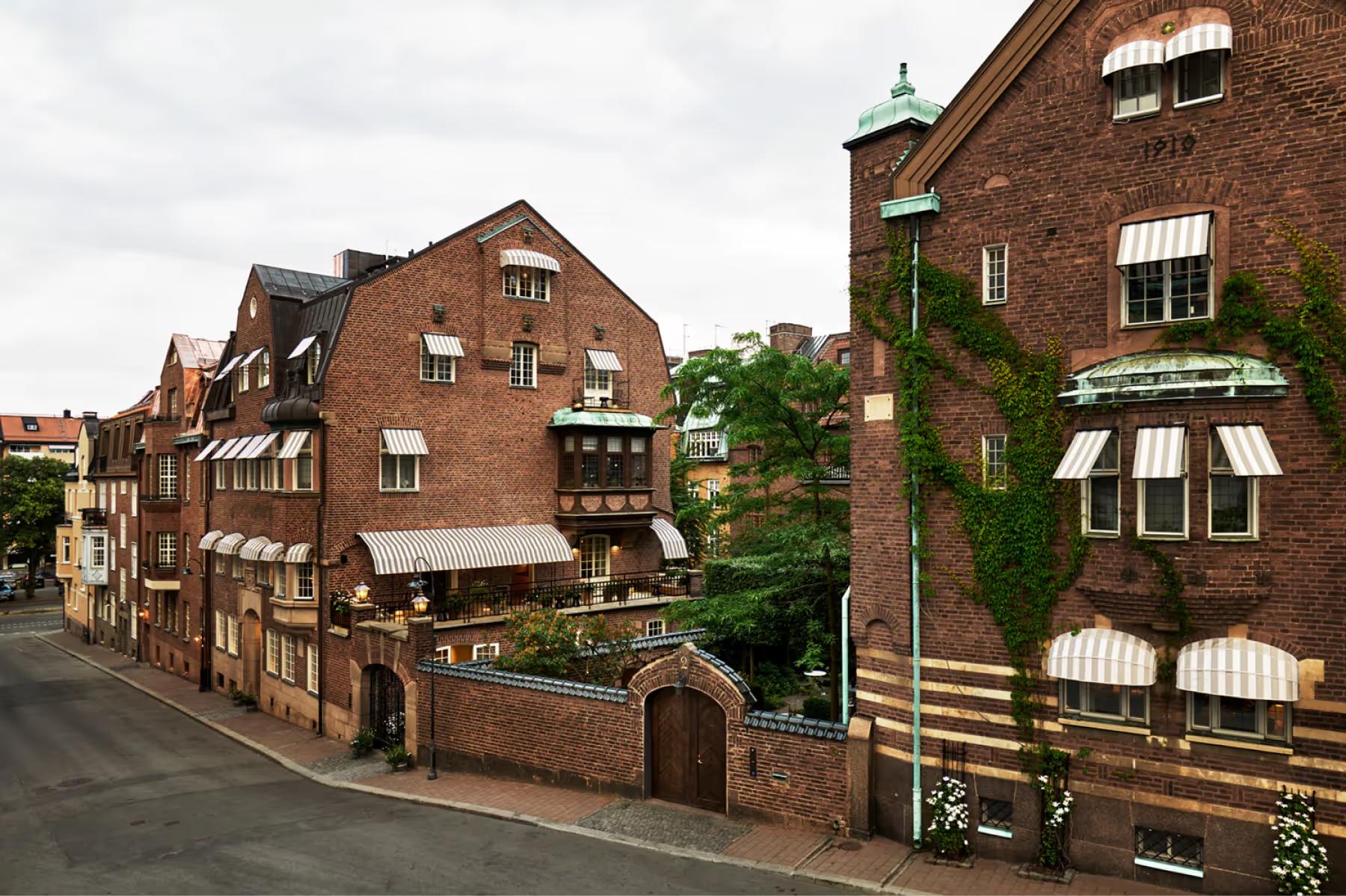 Red brick townhouses with windows, hedges, and winding street in Stockholm residential area