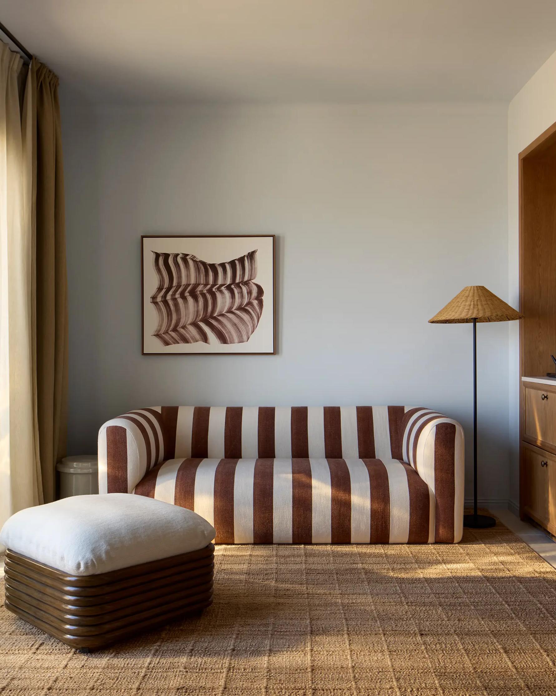 A Delos room with a brown and white striped sofa, a woven rug and a cane lampshade