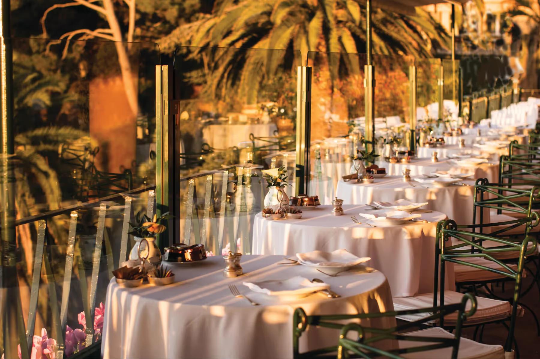 Splendido: an outdoor dining terrace with white tablecloths, tropical plants, and sea backdrop