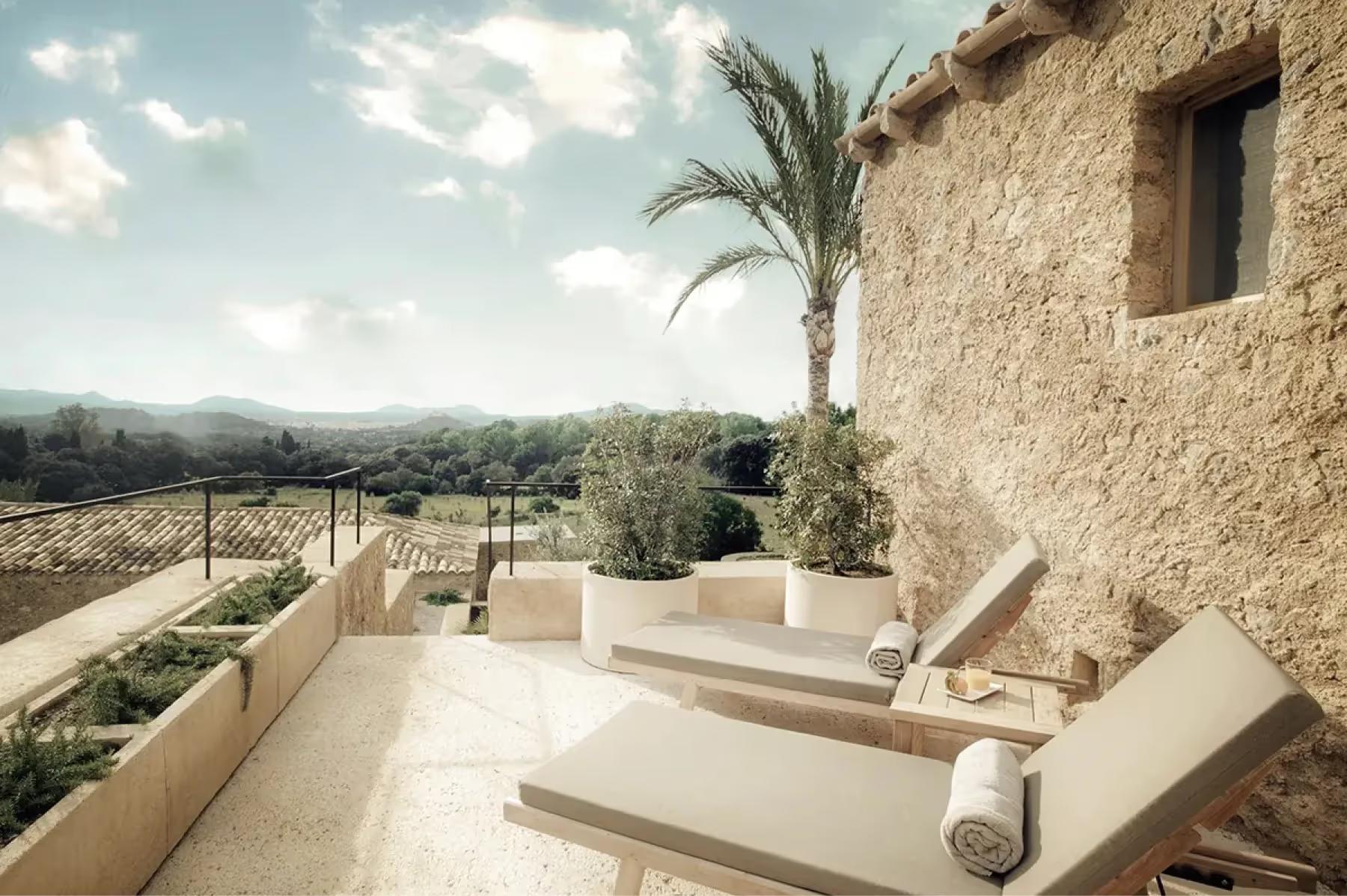 Outdoor terrace of restored stone casita with lounge seating, olive trees, and mountain vistas at dusk