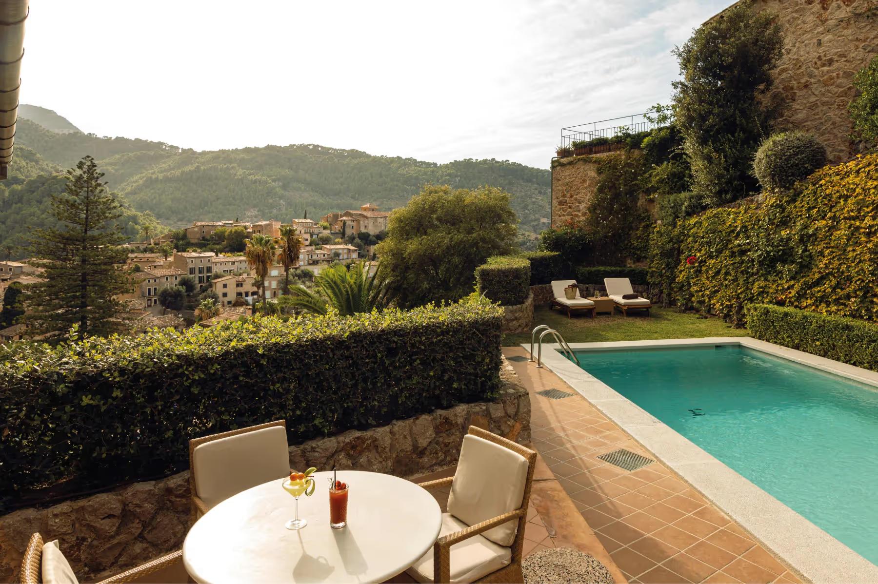 La Residencia: private terrace overlooking a hillside with turquoise pool, dining table, and mountain backdrop