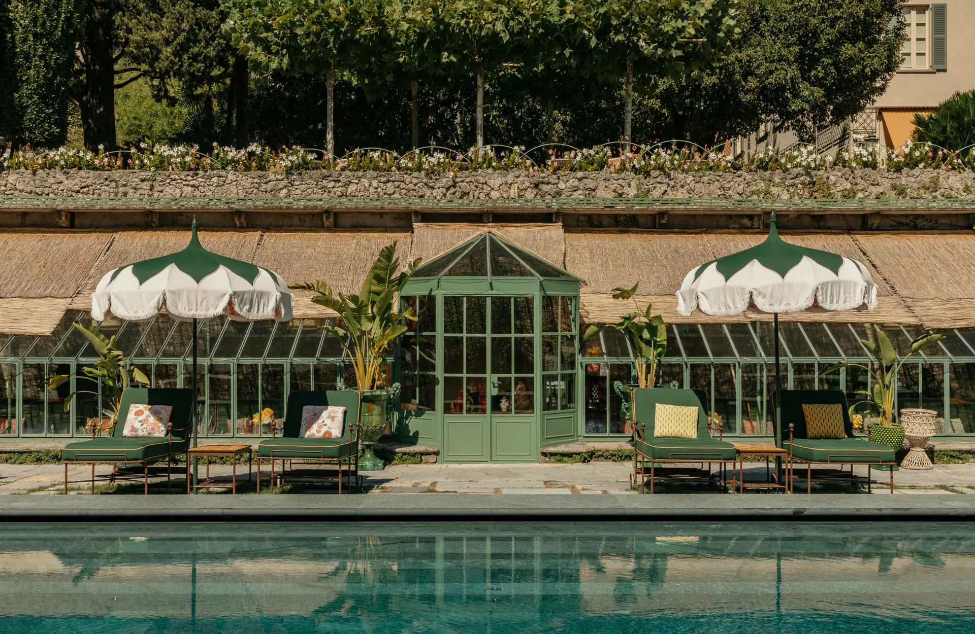 Passalacqua: a stone terrace with loungers and white umbrellas beside a reflective pool