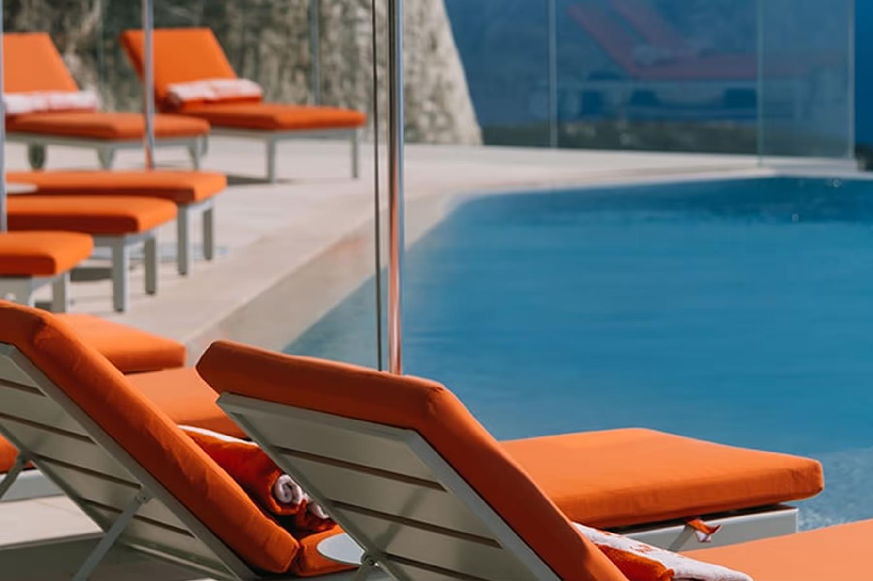 Orange lounge chair by pool with ocean backdrop