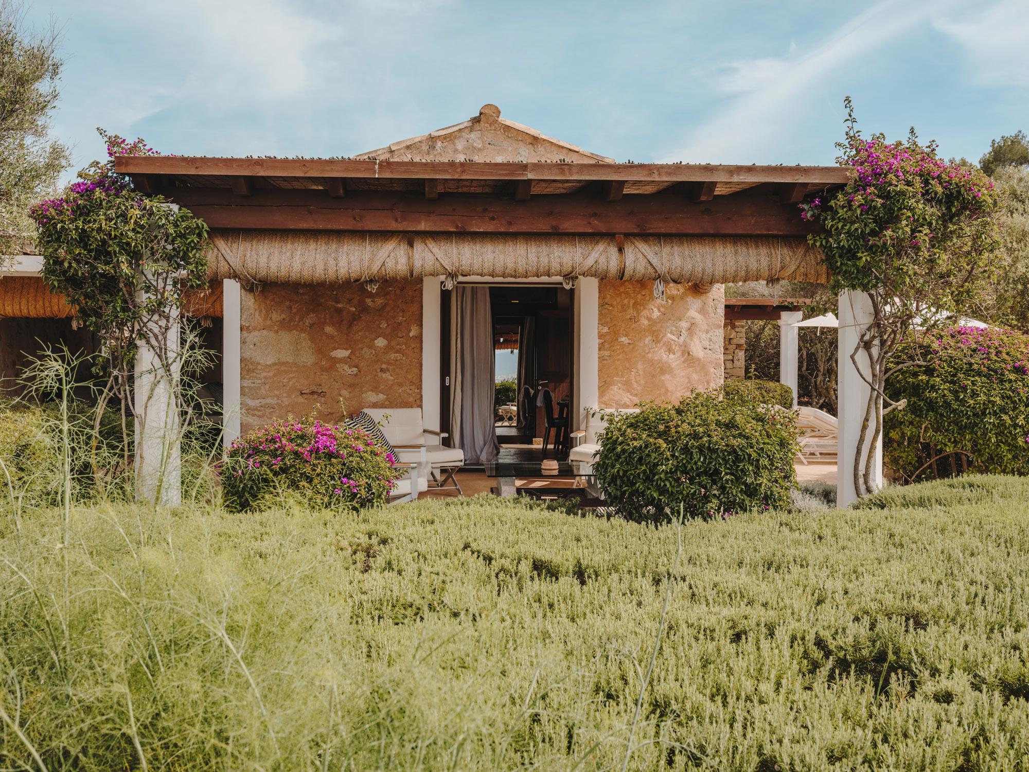 Cap Rocat: a terracotta pavilion with white columns and thatch roof, ringed by magenta bougainvillea and Mediterranean greenery