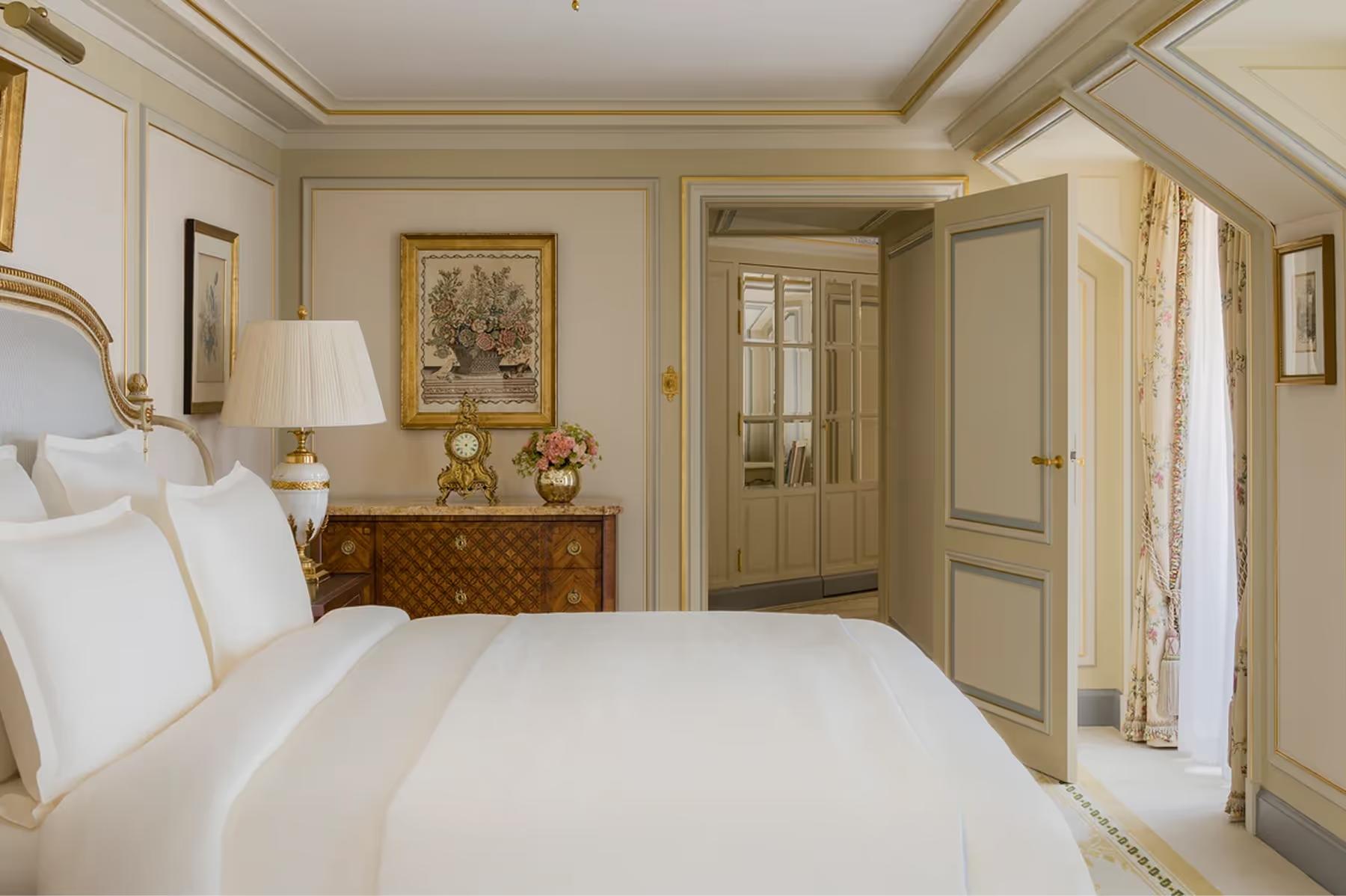 Ritz Paris: a bedroom with parquet floors, framed artwork, gilt accents, and cream color palette