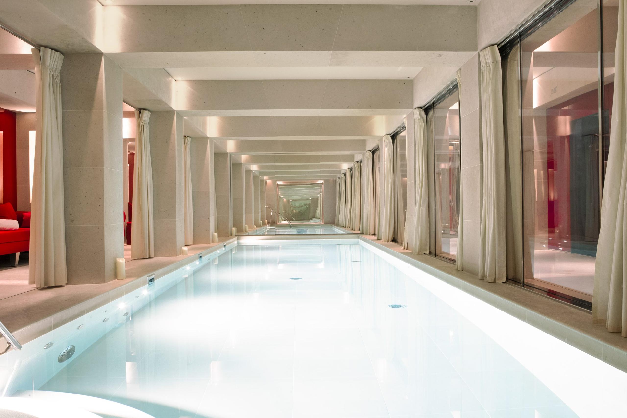La Réserve Paris: an indoor pool with pale blue water and cream marble columns lining both sides