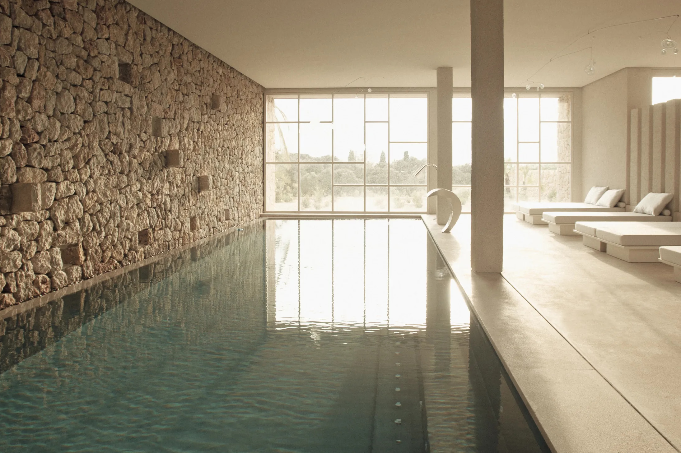 Es Racó d’Artà: indoor heated pool pavilion with natural stone walls and skylight illumination