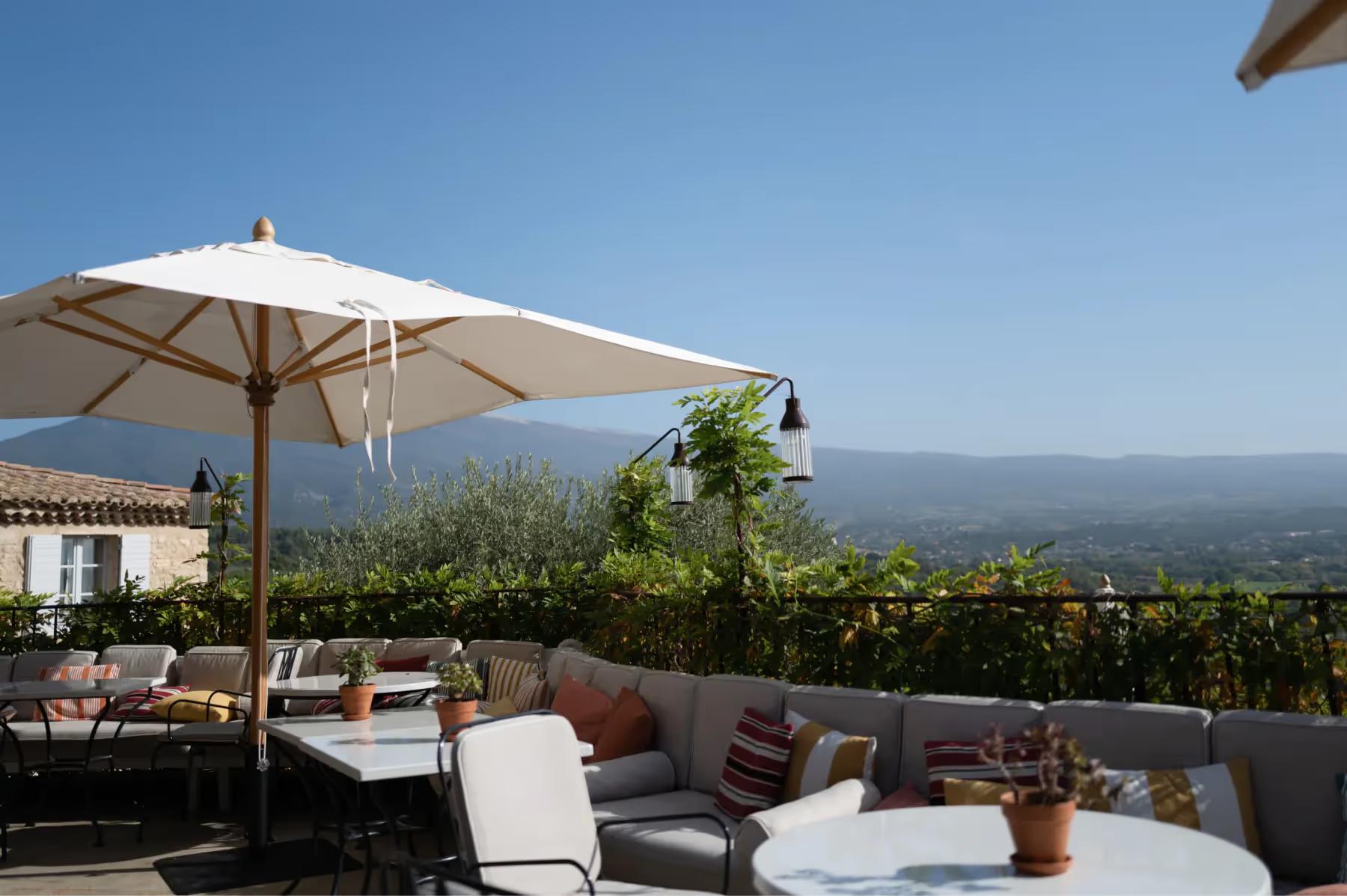 Hôtel Crillon le Brave: a terrace dining area with white umbrella, mountain views, and table seating with landscape backdrop