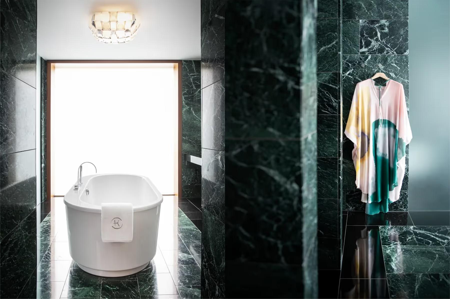 Chenot Palace Weggis: spa-style bathroom with green marble, soaking tub, and sculptural bath fixtures