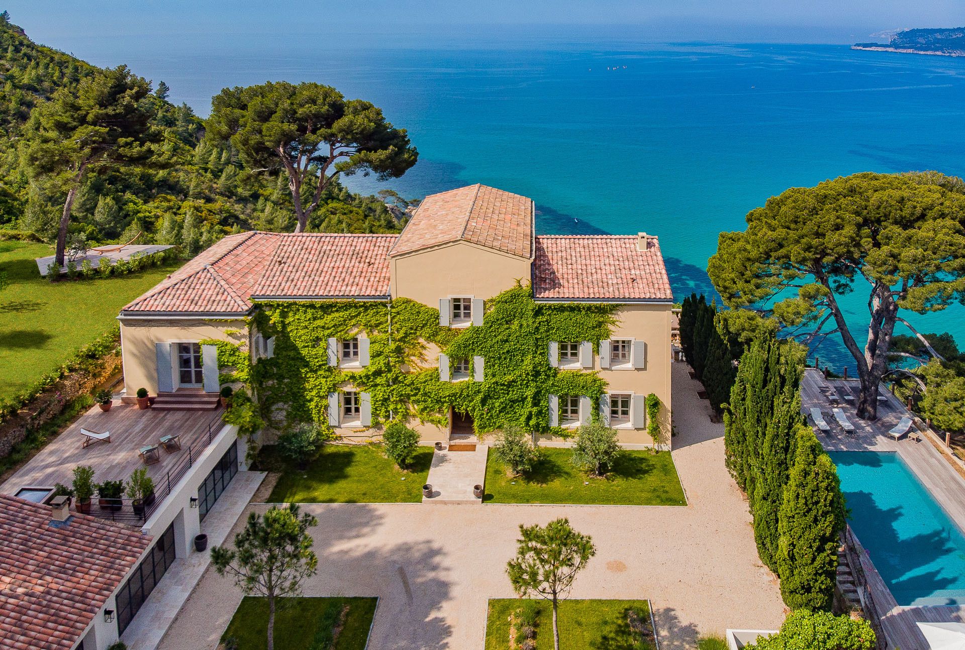 An aerial view of Le Domaine de Canaille, a stone house with a swimming pool set above the sea among pine trees in Cassis