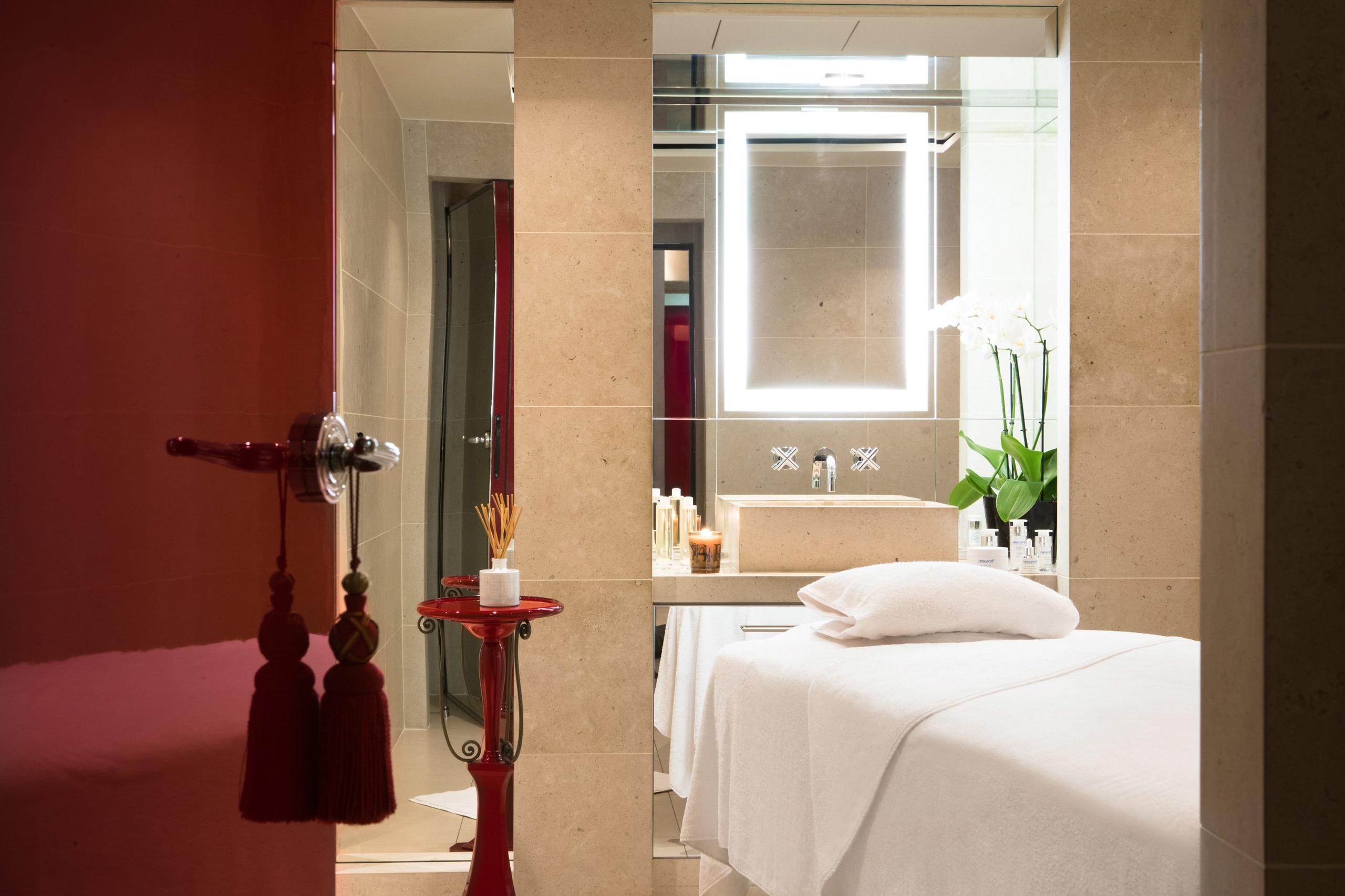 A spa treatment room with deep red accents and a massage table with white linens