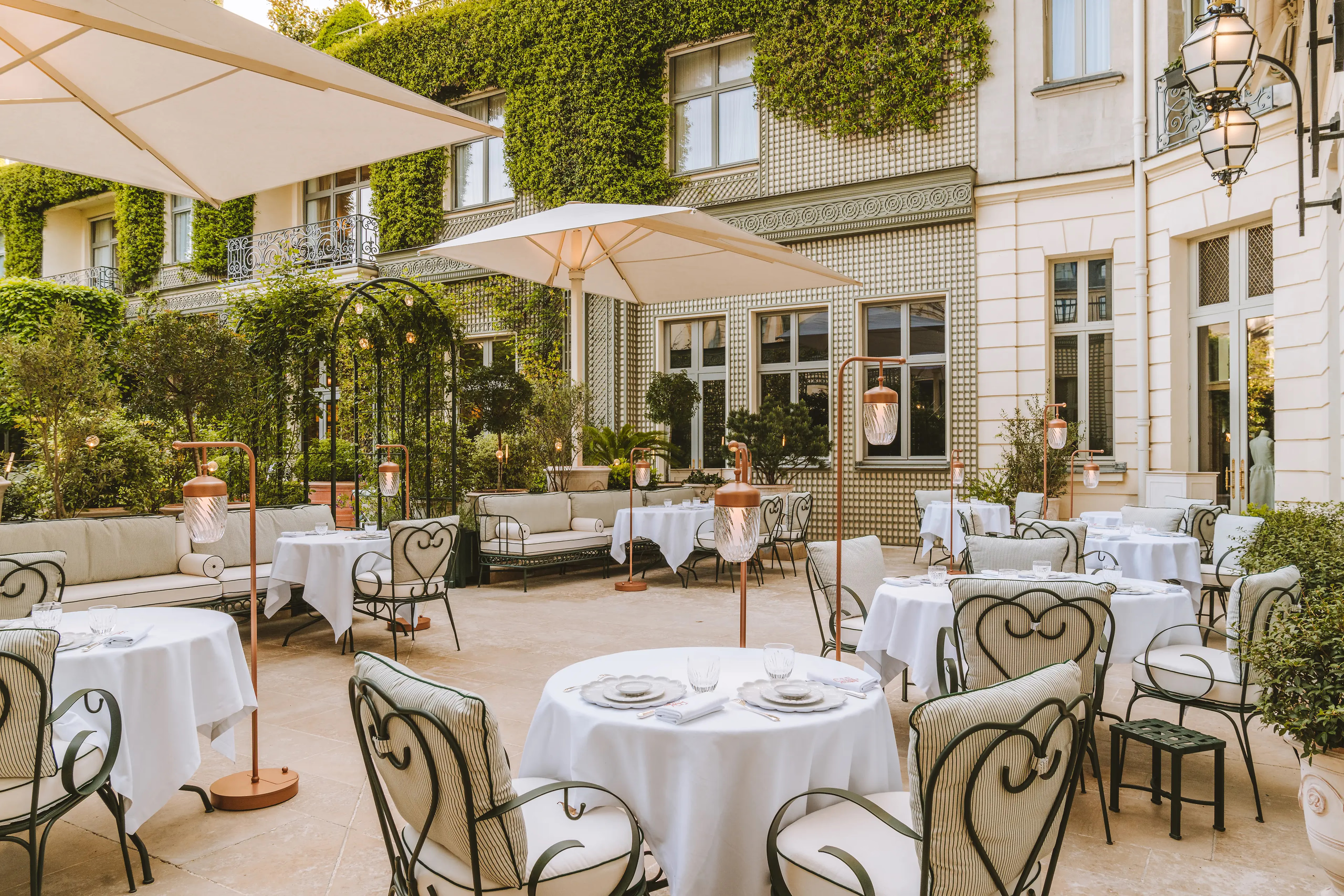 Ritz Paris: an outdoor terrace dining area with white tablecloths, bentwood chairs, and garden surroundings
