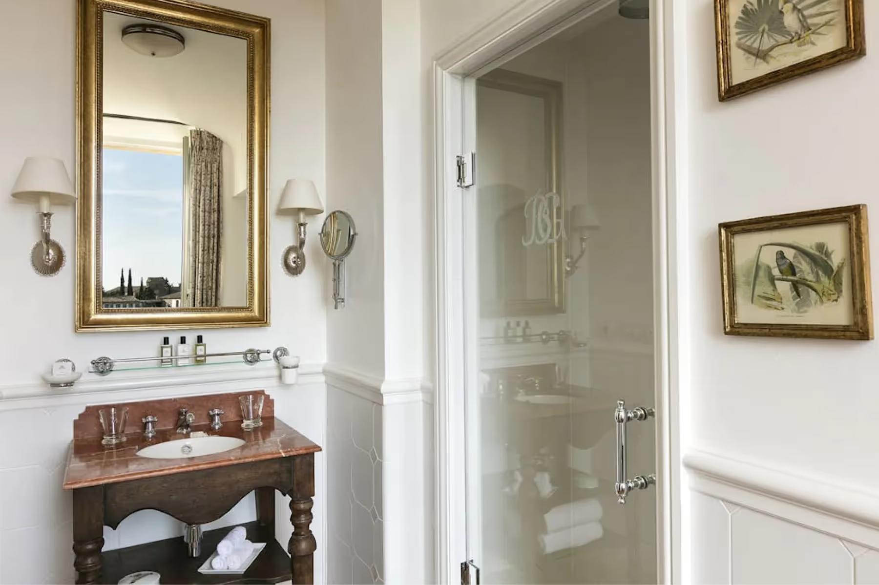 Bathroom vanity in natural wood with round mirror and framed botanical art