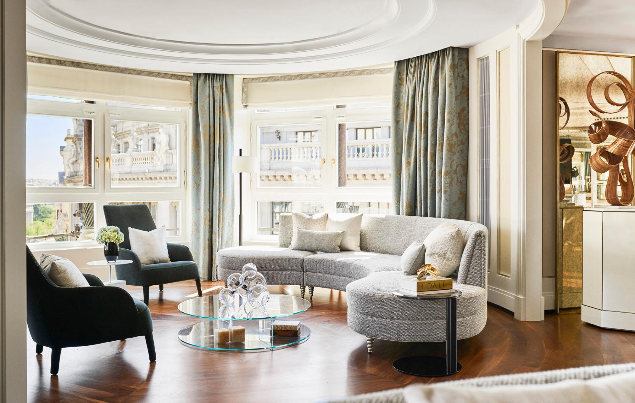 Living area with curved ceiling, gray upholstered seating, wood flooring, and city skyline views