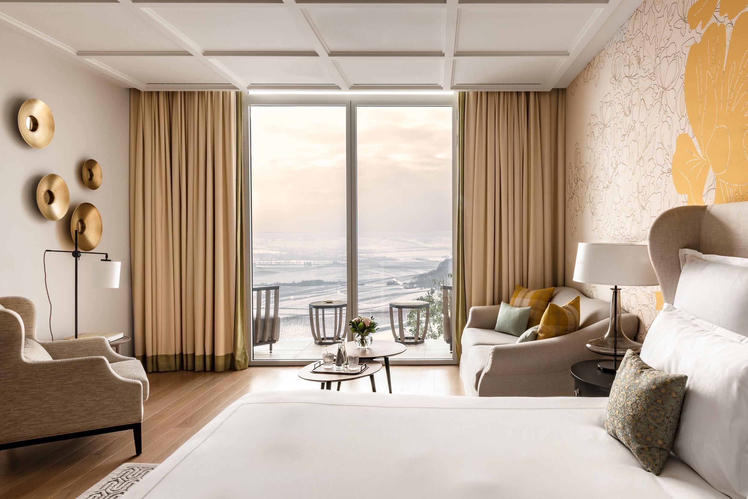 Royal Champagne Hotel & Spa: bedroom with mustard accents, natural wood details, and glass doors framing water views