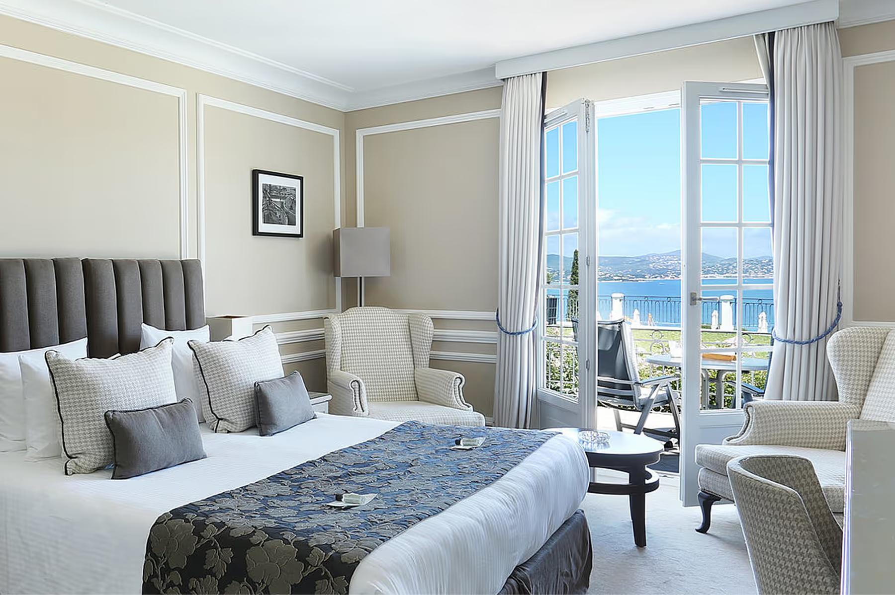 Guest bedroom with blue headboard and balcony opening to distant sea views