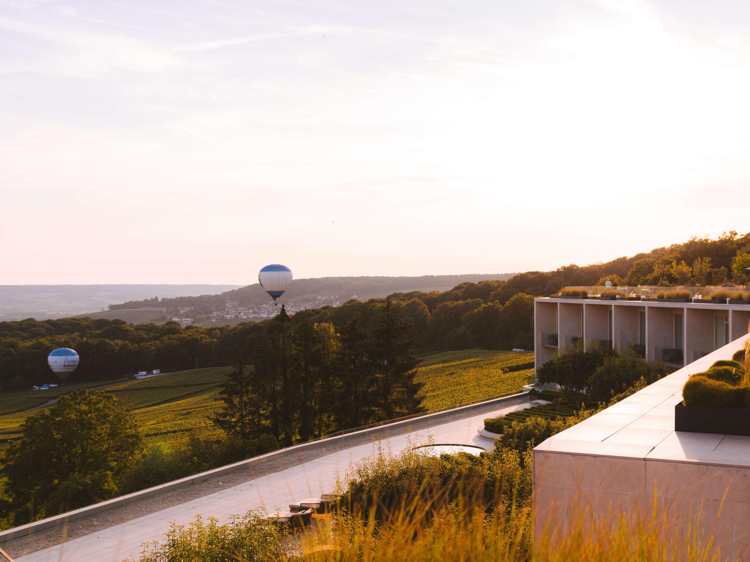 Royal Champagne Hotel & Spa: terrace at dusk overlooking vineyards with hotel structure in soft evening light