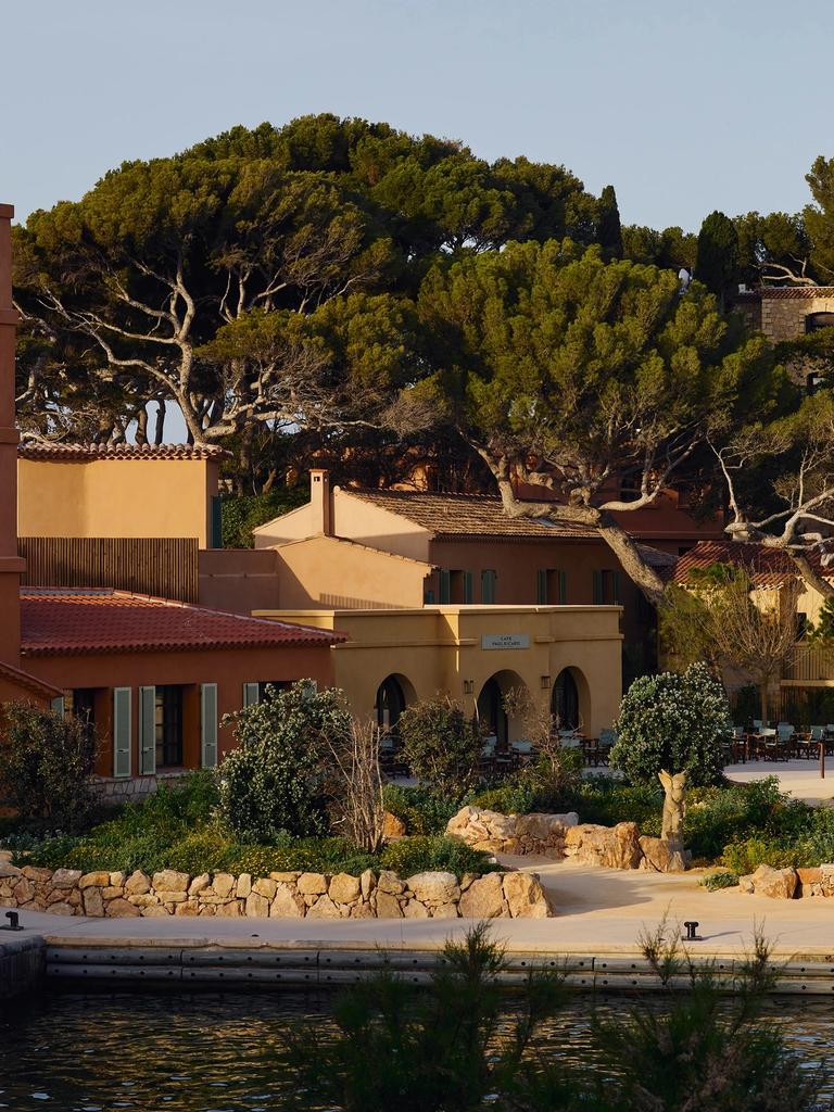 Café Paul Ricard and ochre houses with red tile roofs and green shutters under umbrella pines, by the harbor
