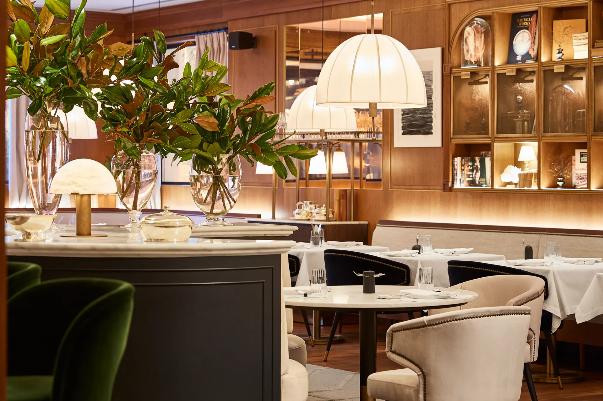 Rosewood Villa Magna: a restaurant with wood paneling, upholstered chairs, and warm ambient lighting