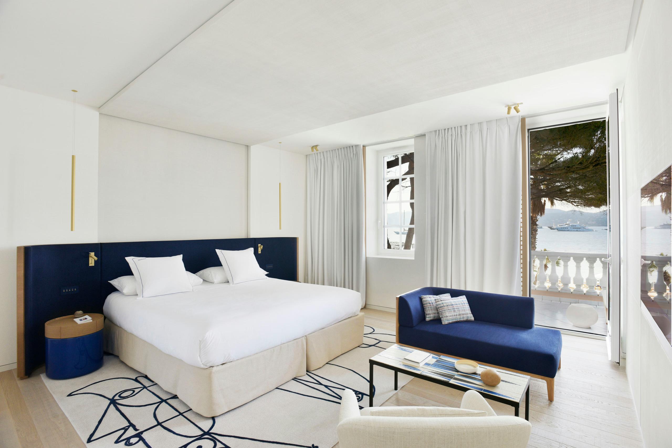Contemporary bedroom with navy headboard and sea-view terrace