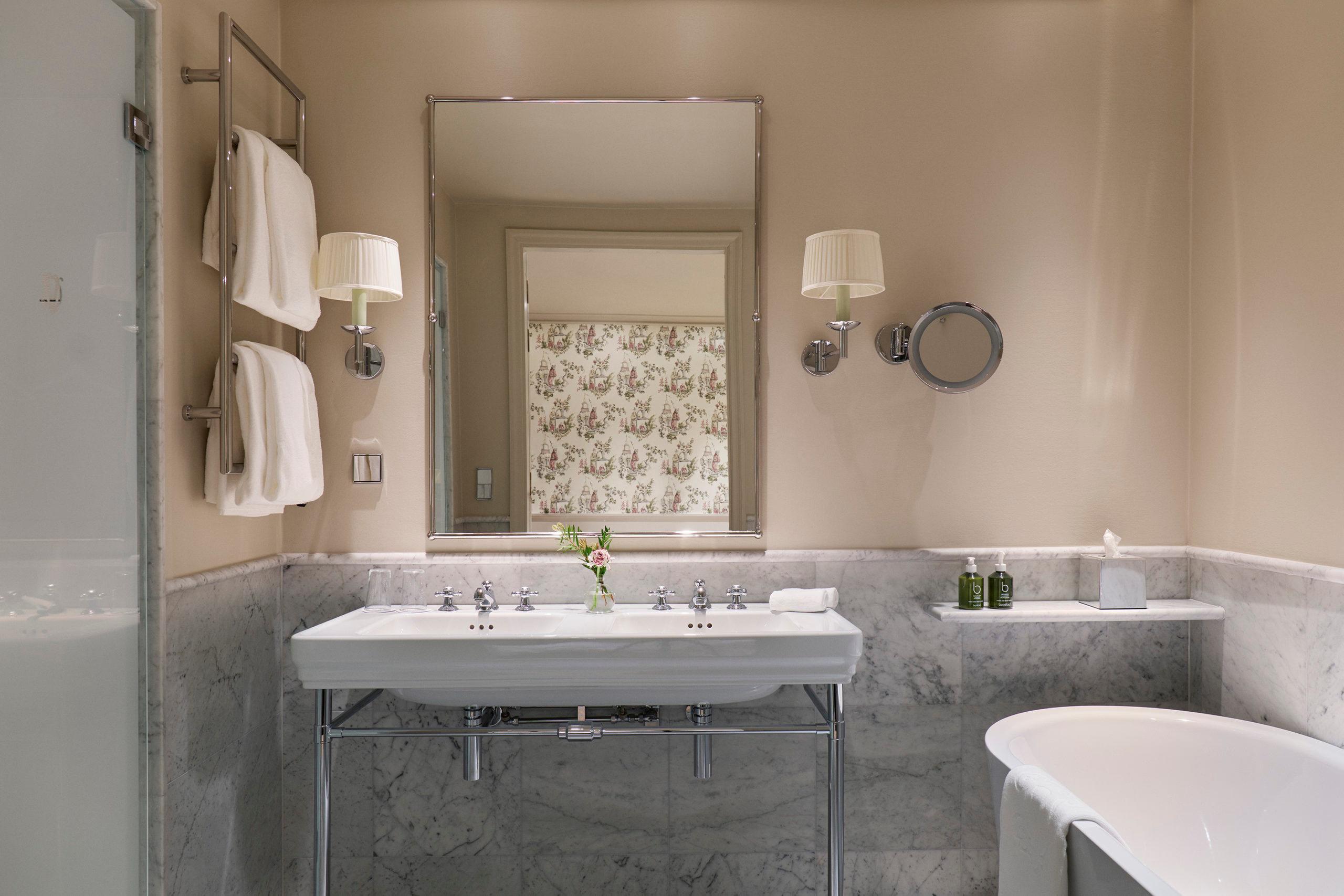Marble bathroom with vessel sink, brass fixtures, and vintage-style mirror