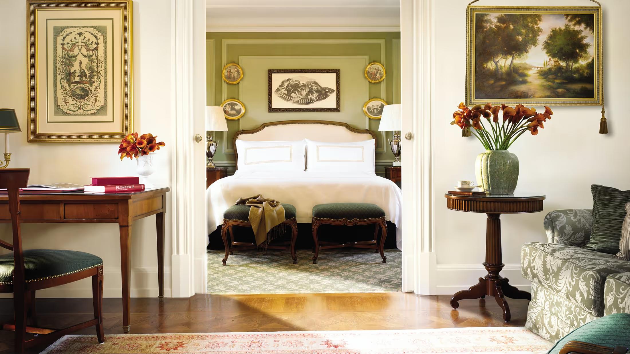 Four Seasons Hotel Firenze: a guest suite with cream-colored walls, an ornate fireplace, and framed artworks