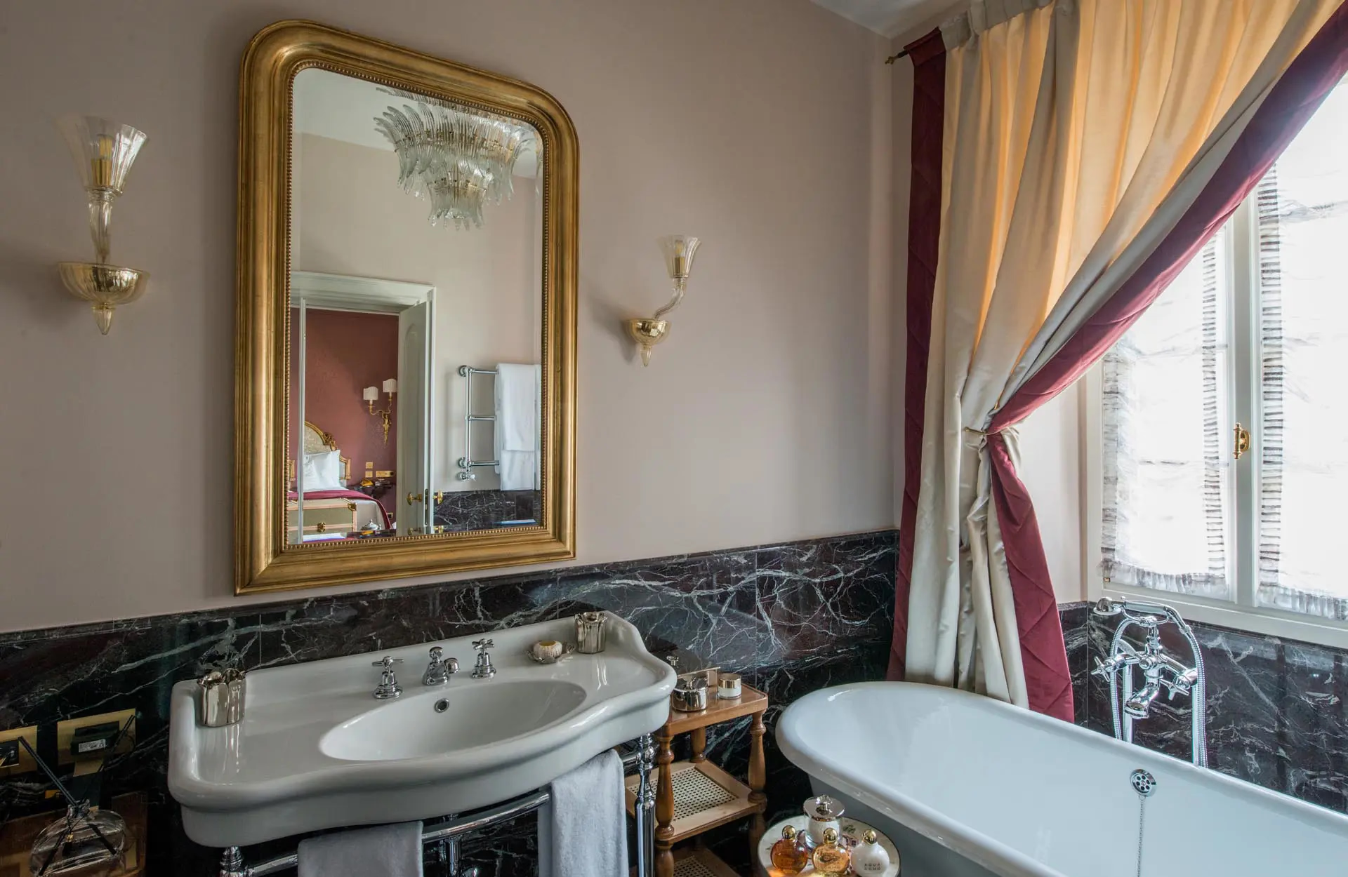 Passalacqua: a bathroom with gold-framed mirror, pedestal sink, and slate accent wainscoting