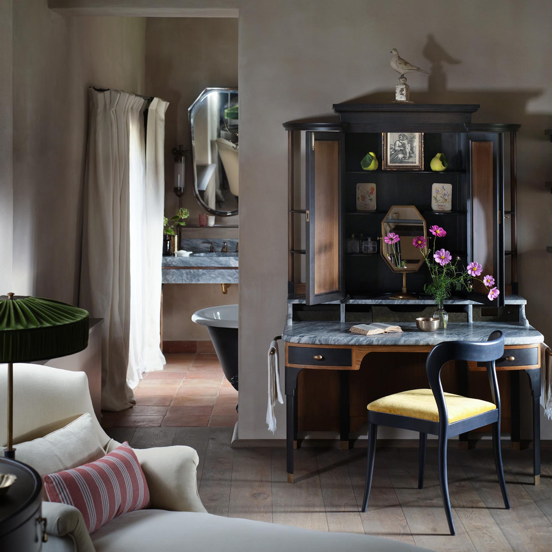 Castello di Reschio: a bathroom with a black clawfoot tub, dark antique cabinetry, and a mirrored vanity nook