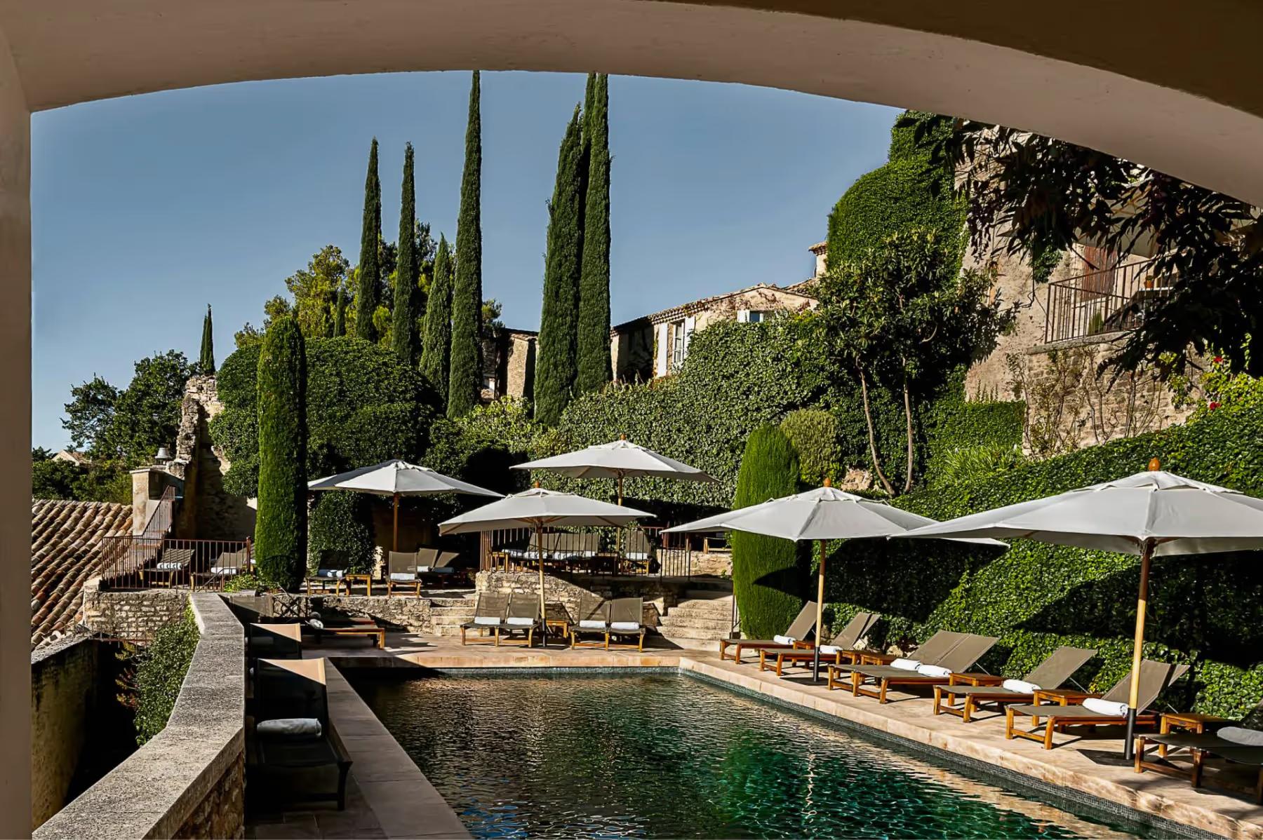 Hôtel Crillon le Brave: a loggia framing the pool terrace, cypress trees, and distant hills under blue sky