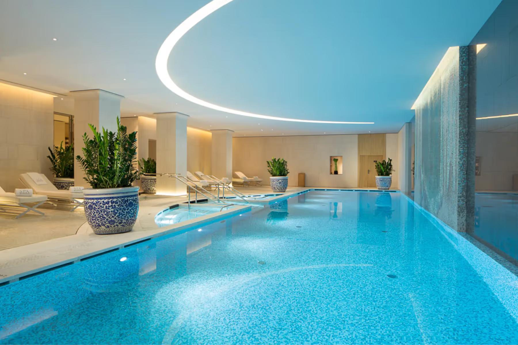 Modern bathroom entrance with glass doors opening to a spa pool with blue water
